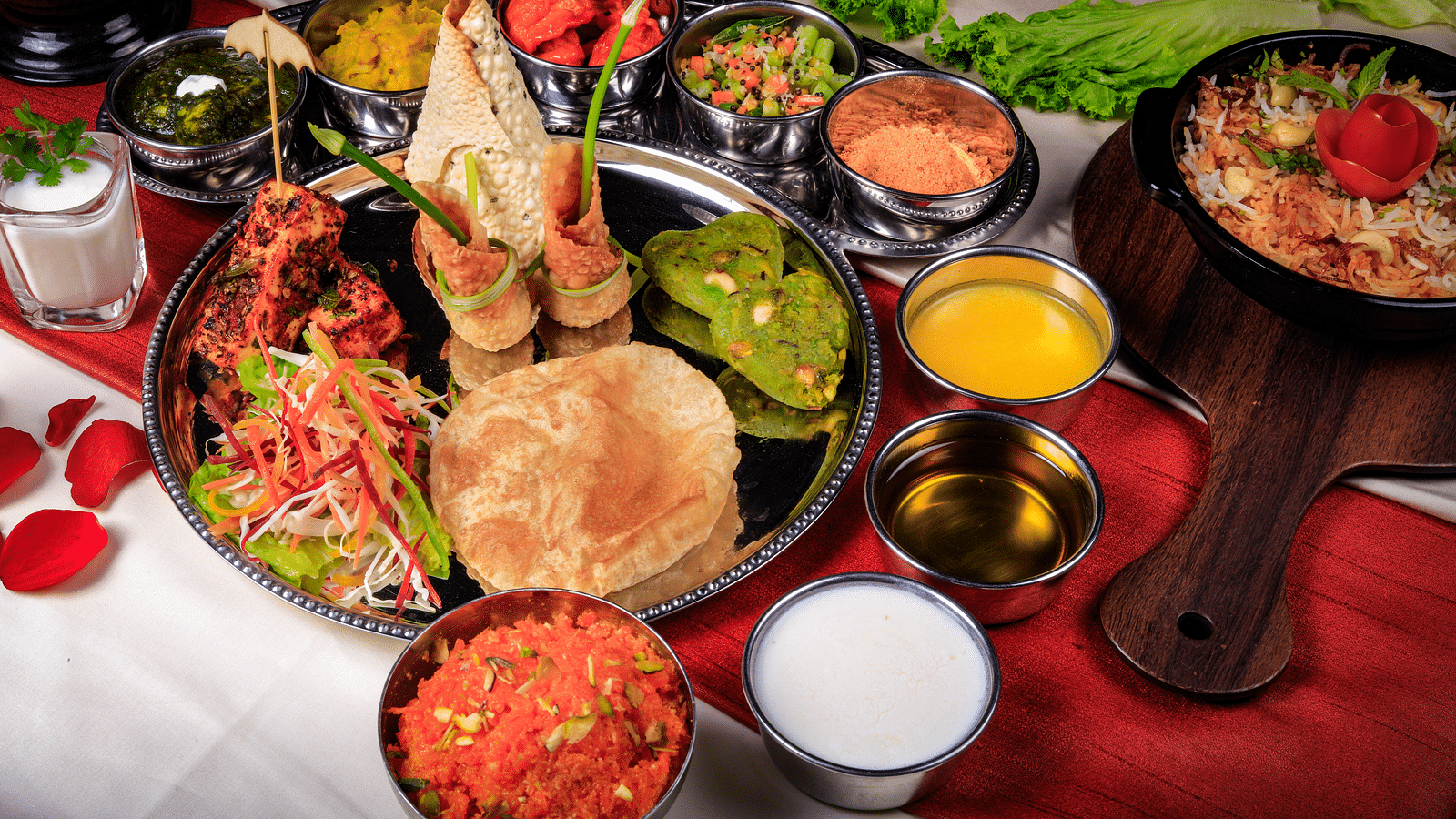 A thali meal with various dishes, including rice, curry, vegetables, and bread.