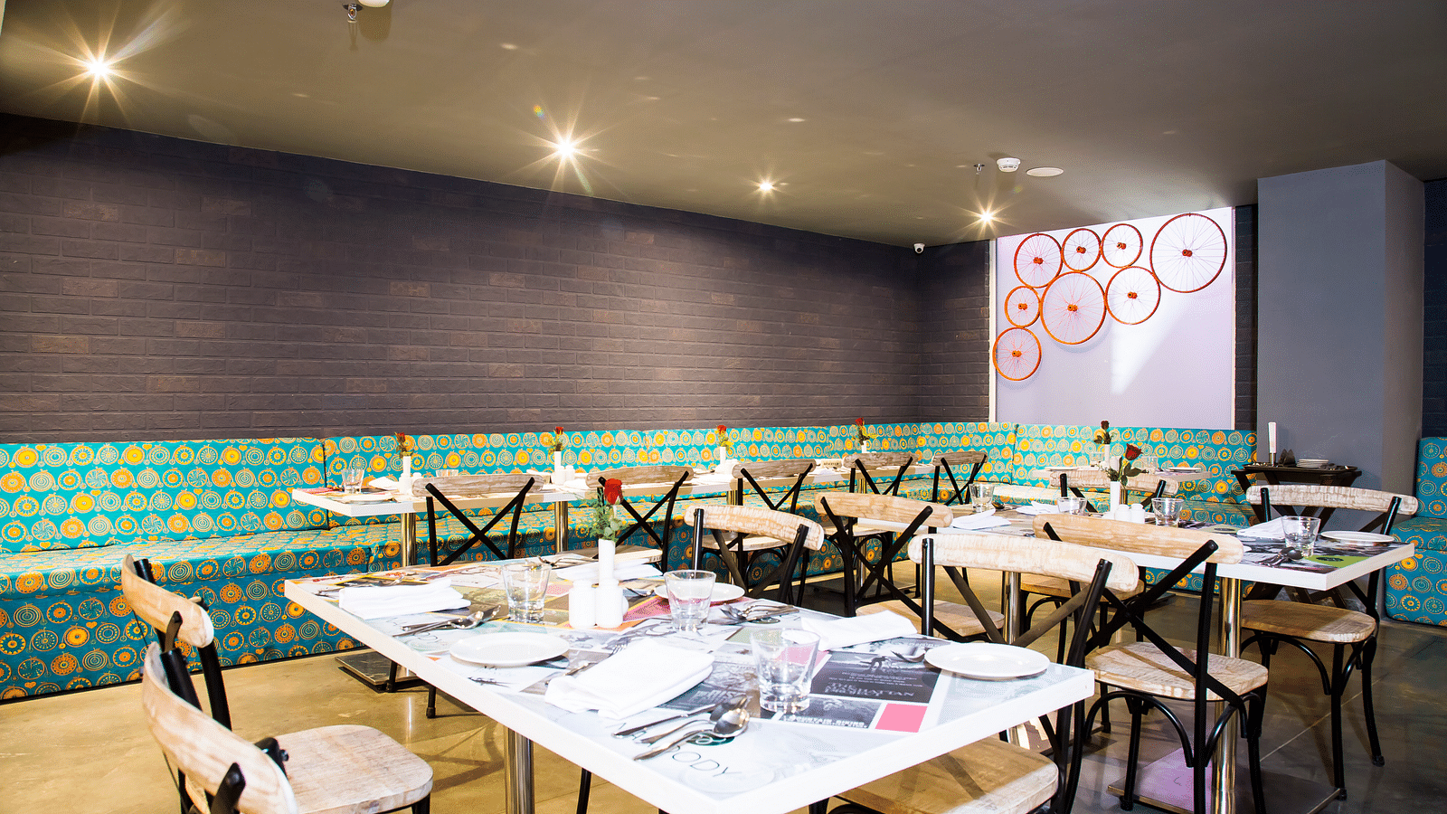 Modern restaurant interior with turquoise banquettes, marble-topped tables, and geometric wall art | Regency Tirunelveli By GRT Hotels