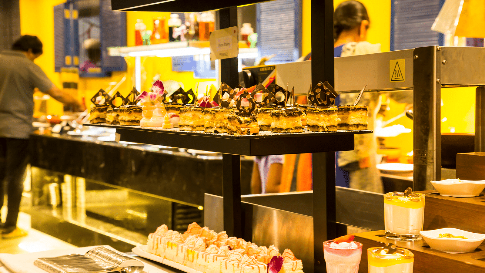 A hotel buffet spread with various desserts, including cakes, pastries, and puddings  | Regency Tirunelveli By GRT Hotels 
