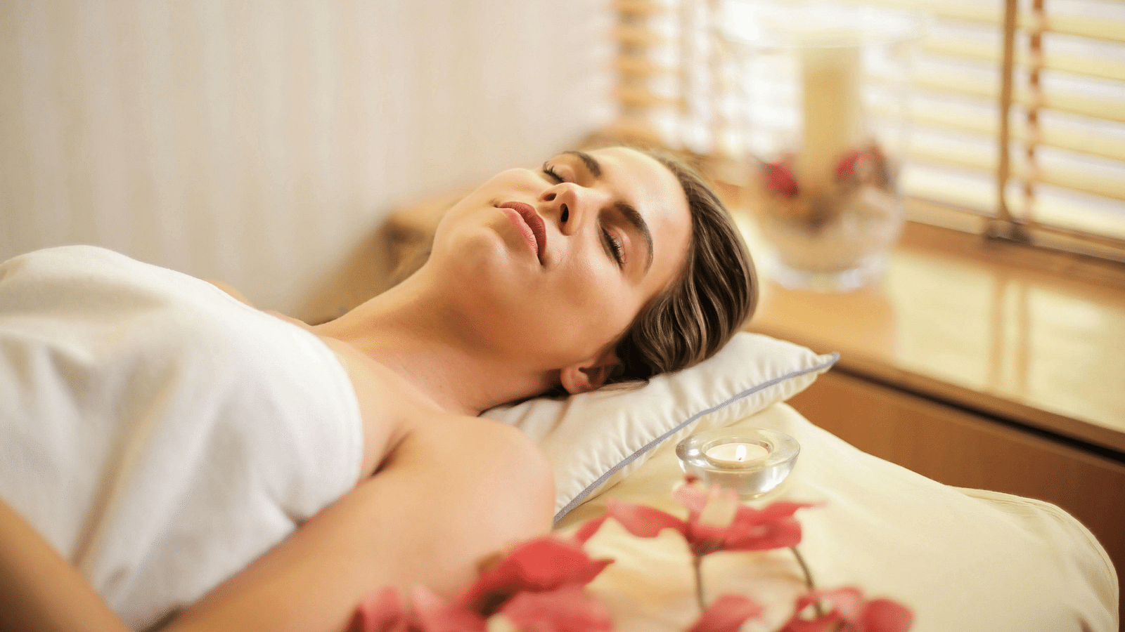 A woman lying down on a bed all relaxed in a brightly lit room.