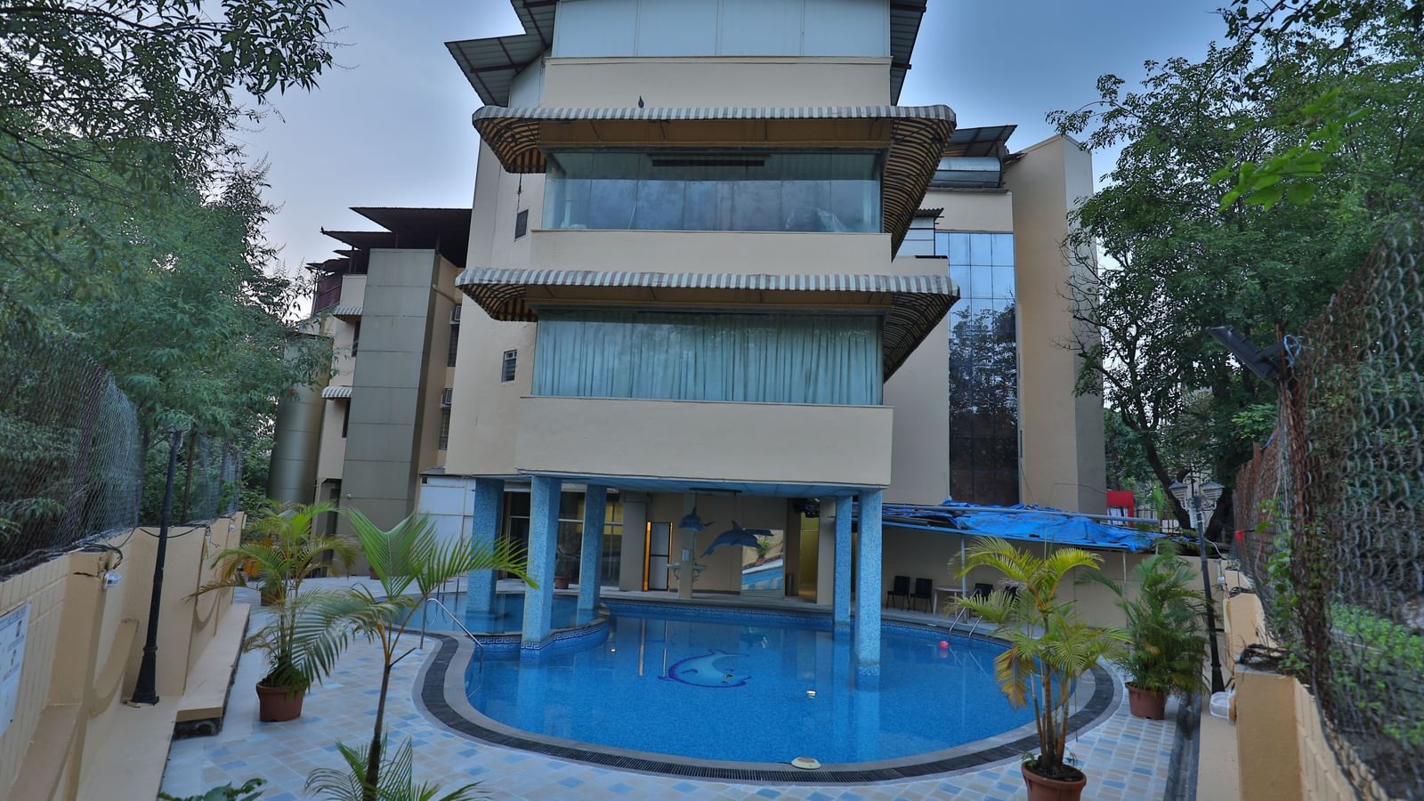 The exterior of a multi-story hotel building with a visible swimming pool in the foreground - Retreat Heritage, Lonavala