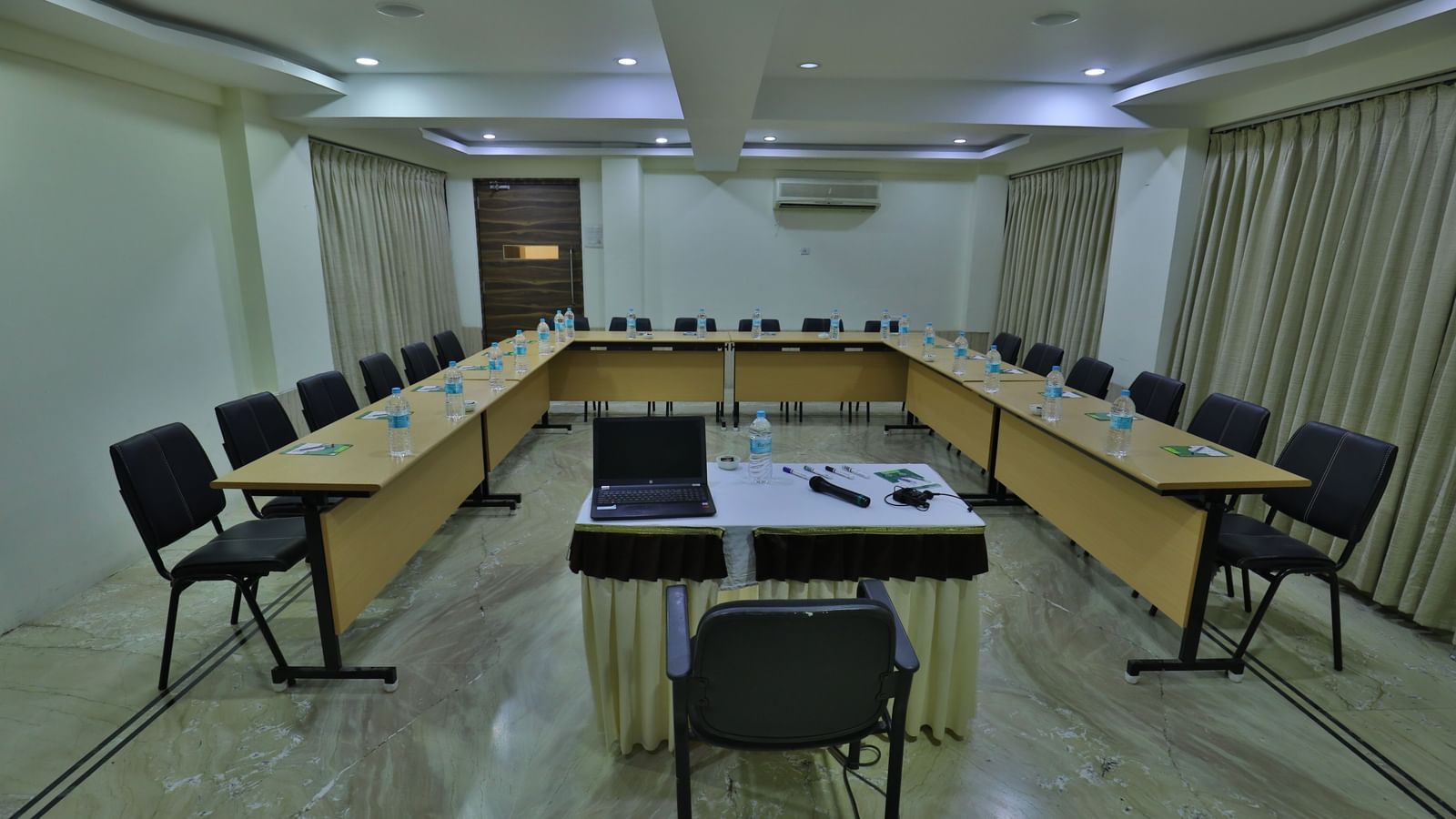 A meeting room with a U-shaped table arrangement, empty chairs, and a small podium at the open end - Retreat Heritage, Lonavala