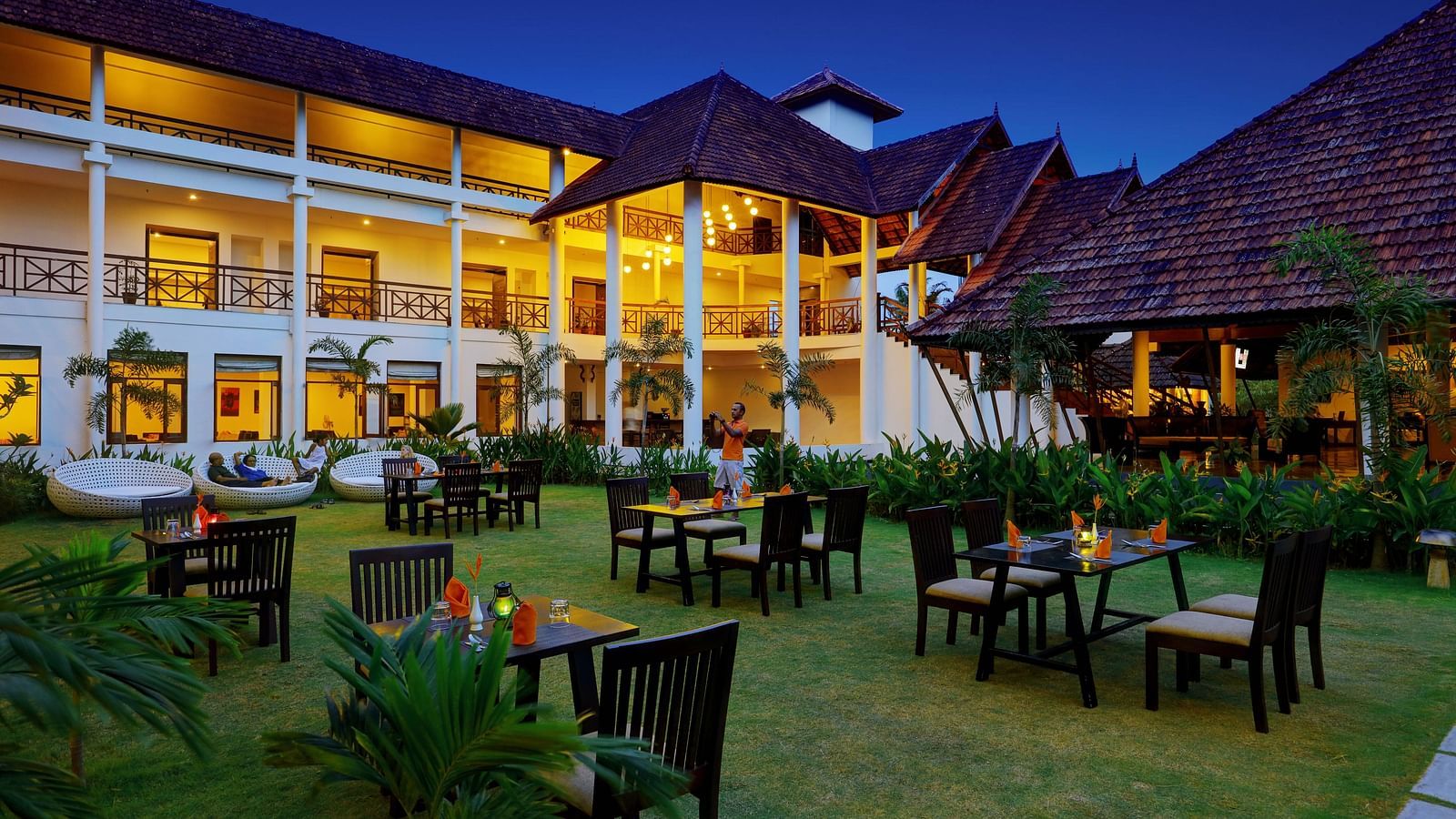 an image of a Lawn with dining tables and chairs for - Rhythm Kumarakom
