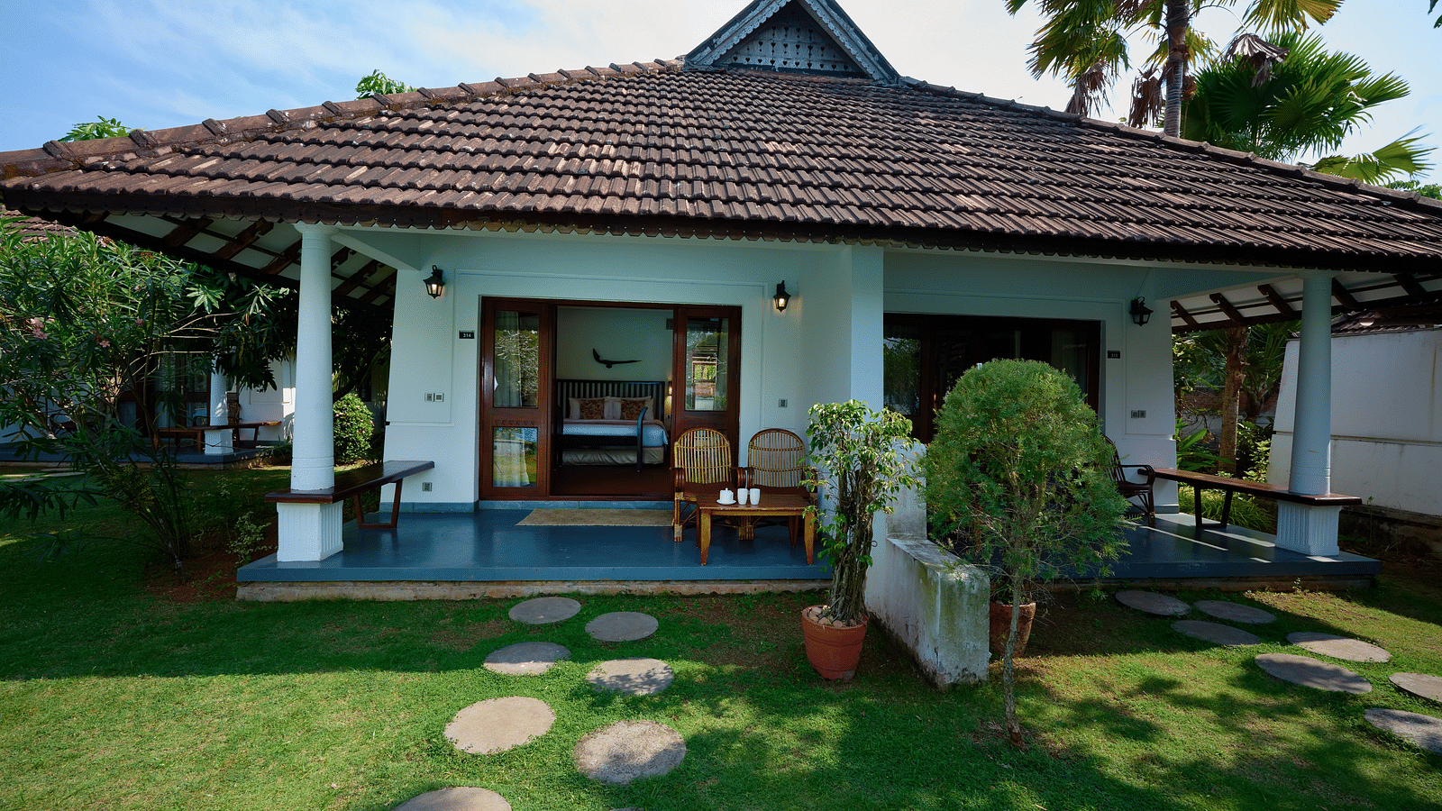 An image of a cottage surrounded by lush green lawn - Rhythm Kumarakom