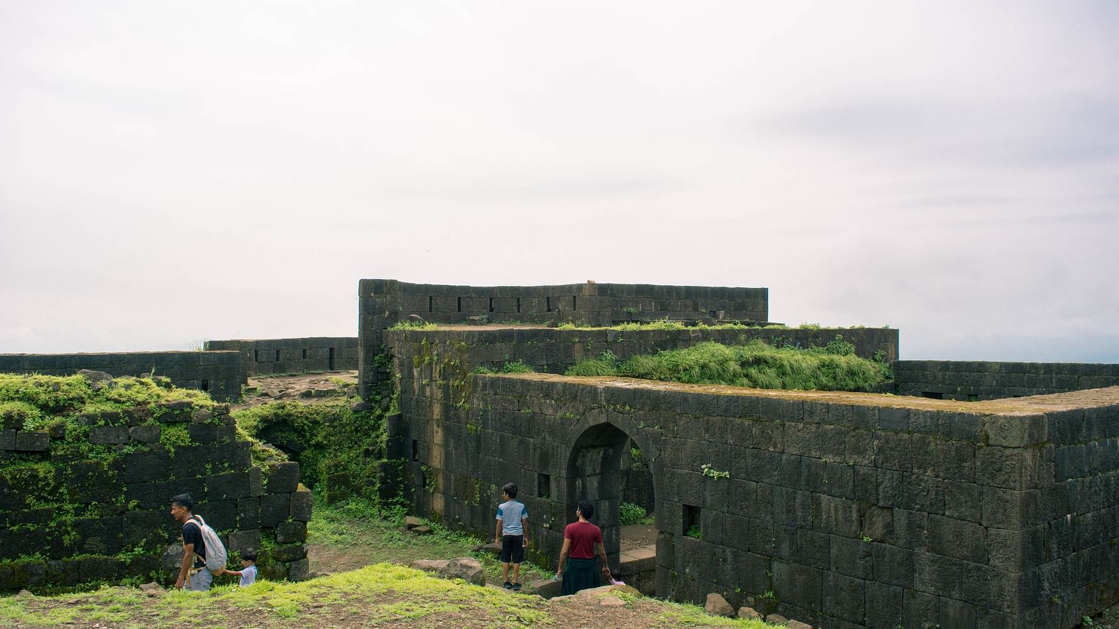 A structure made of stone and covered in moss with white clouds in the background