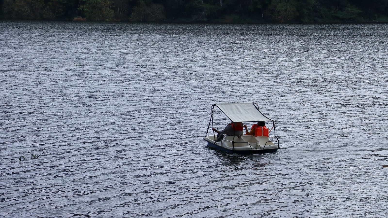 An overview of a lake with two people travelling in a boat.