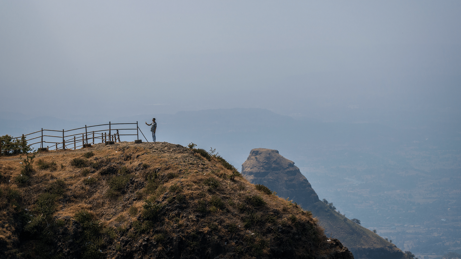 a man standing on a Lion's Point overlooking a valley with other mountains in sight