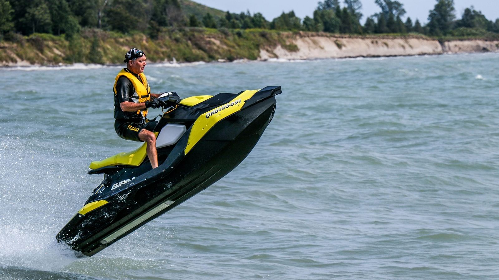 a person riding a jet ski in the ocean with greenery in the background