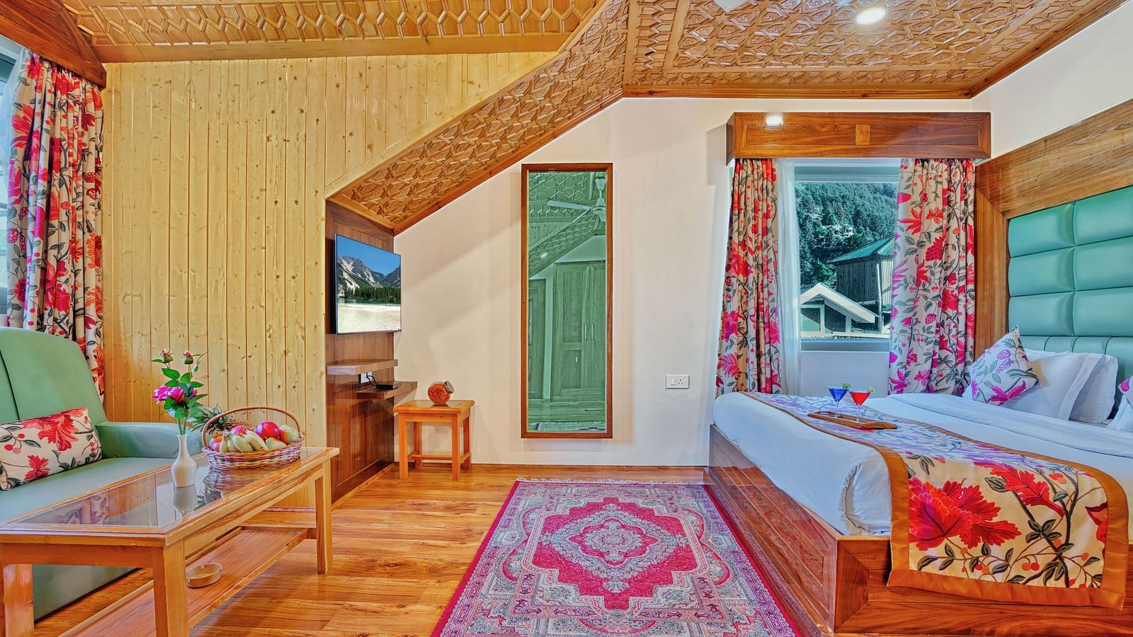 A spacious room at Royal Comfort Regency featuring a sloped wooden ceiling, floral curtains, a bed with a green headboard and a pink patterned rug.