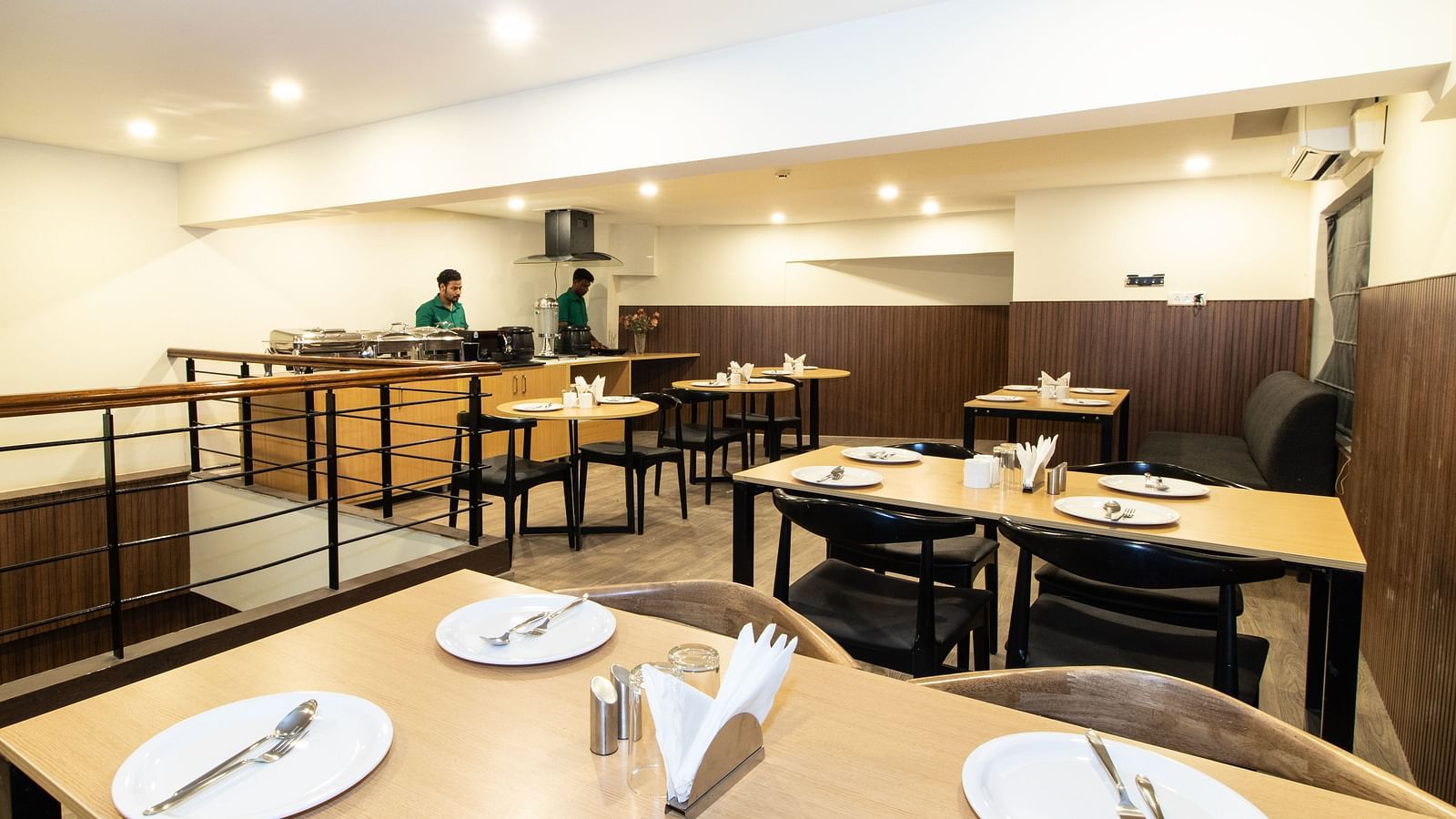 A dining area with wooden tables and chairs in a warm inviting setting - Sanctum Suites Richmond Road, Bangalore