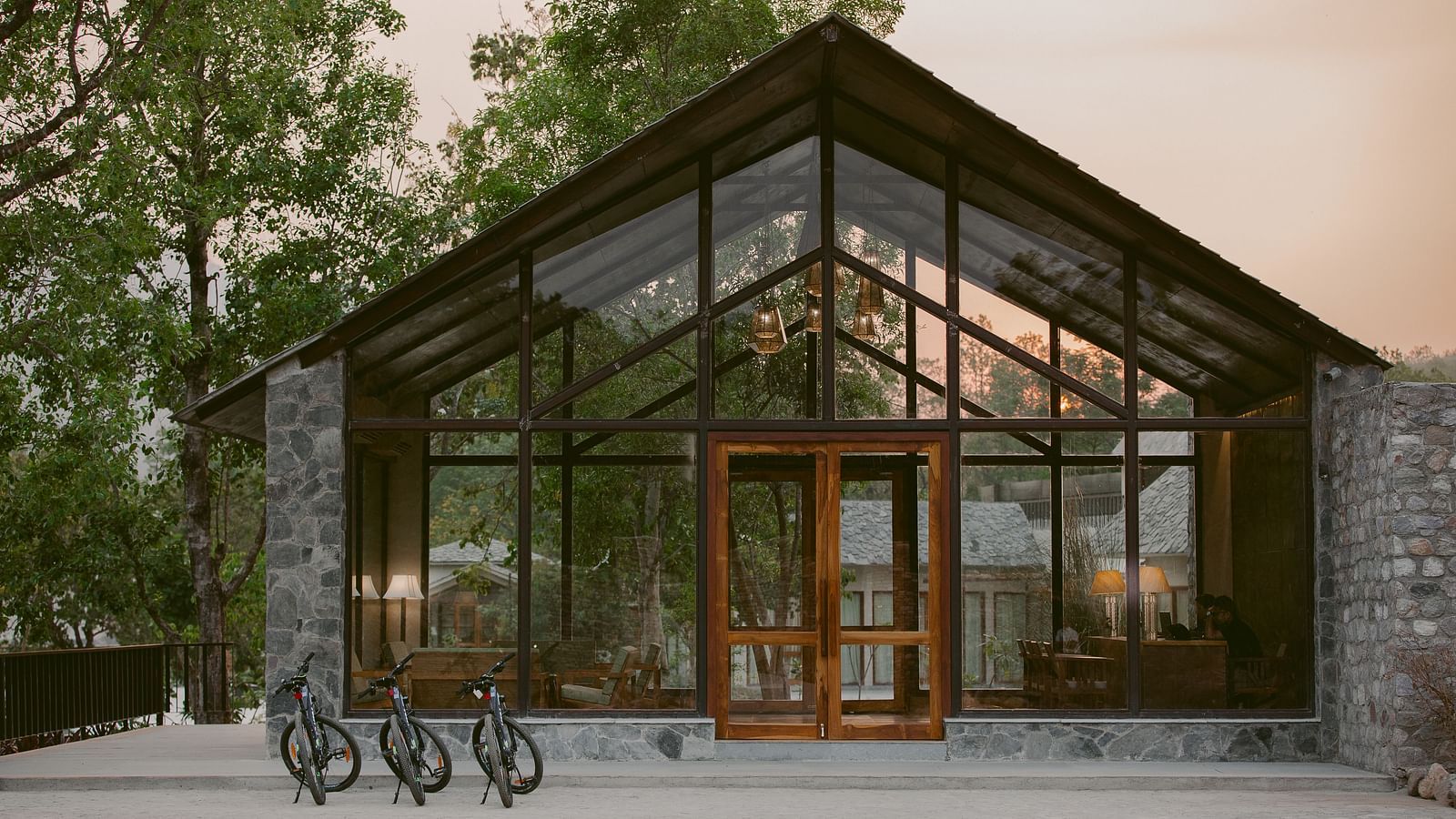 Entrance to Saraca Resort & Spa Corbett with large glass panels and wooden beams