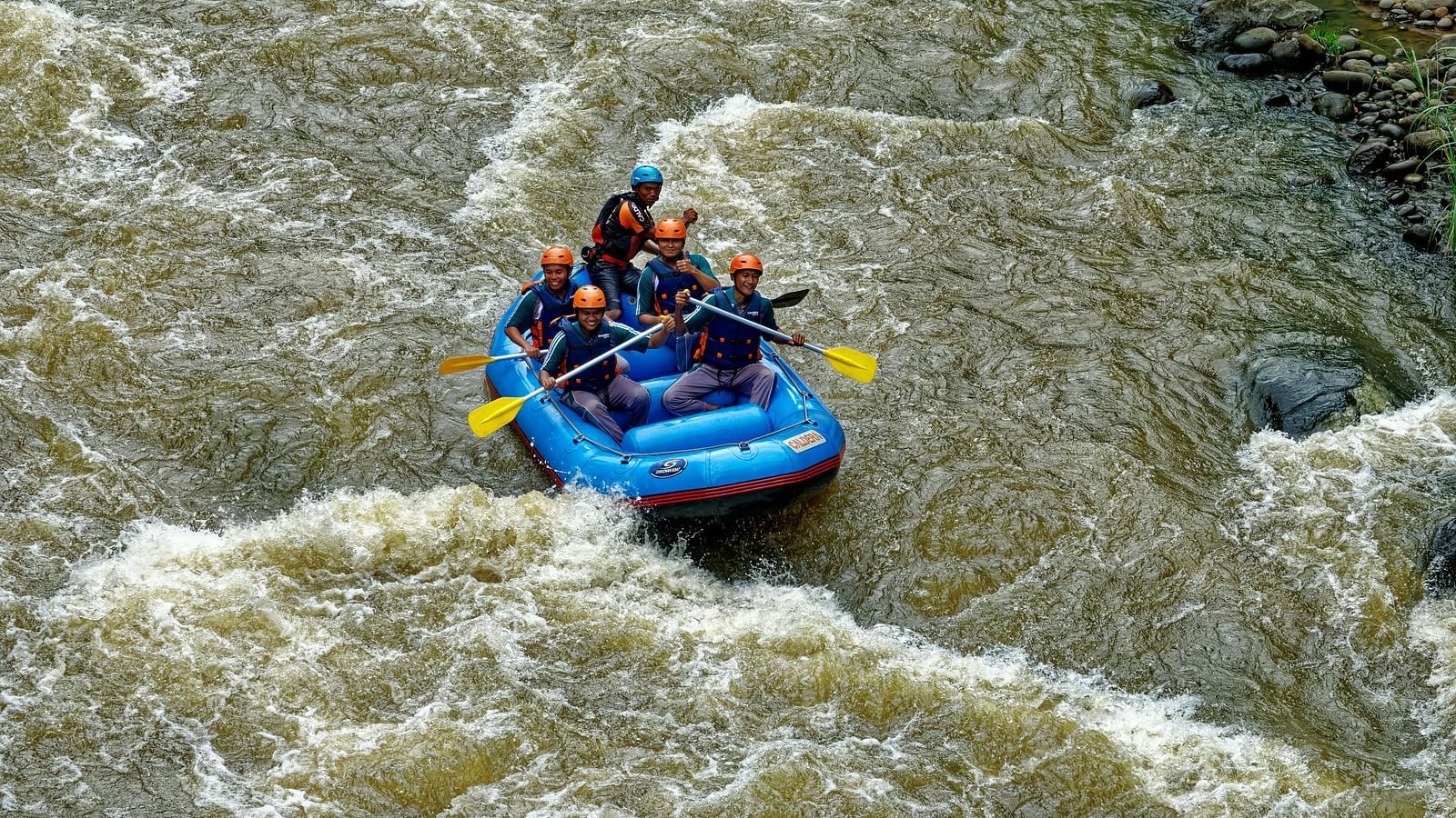 Five men river rafting in an inflatable boat.
