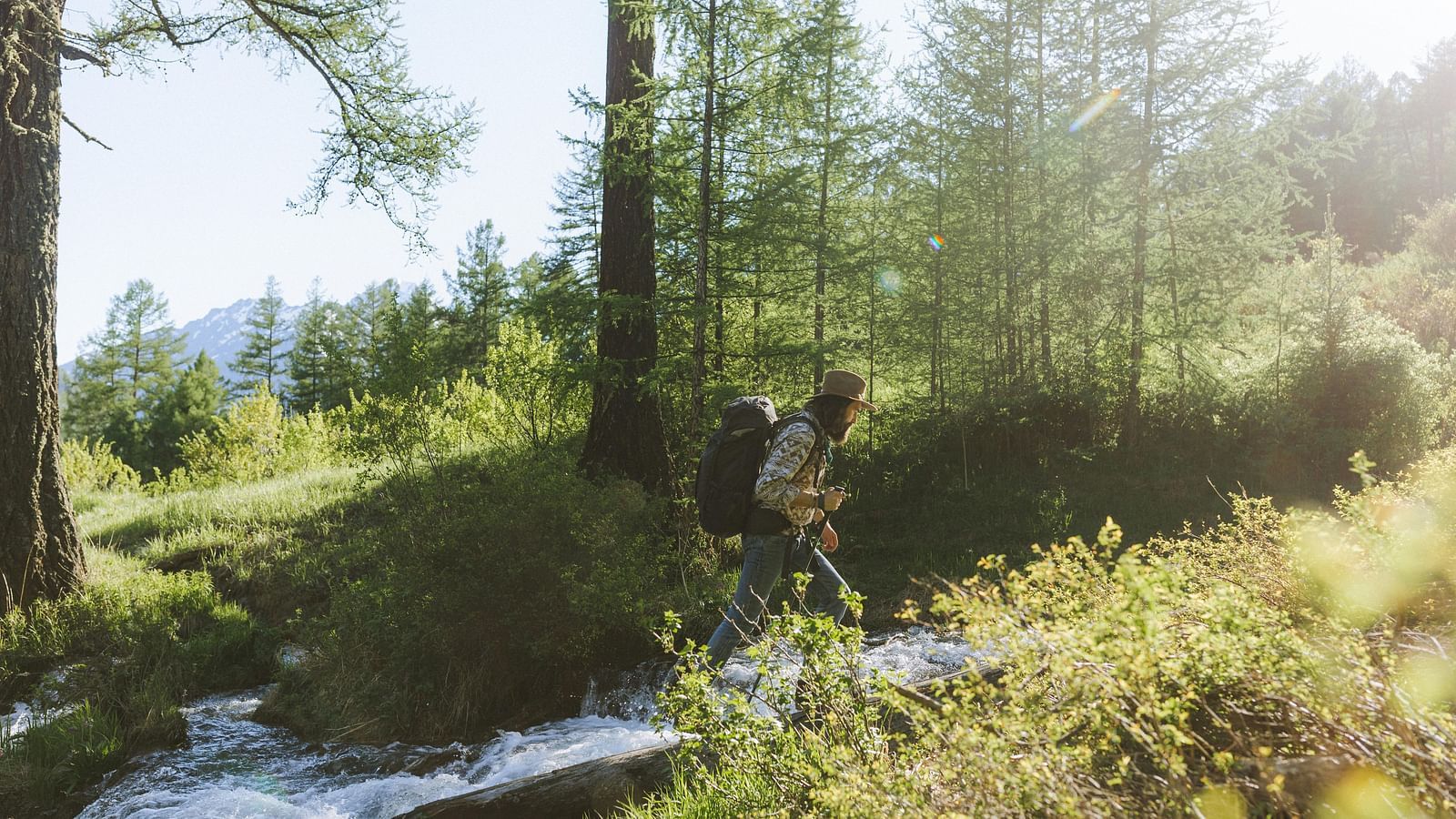 Man trekking near a waterfall surrounded by trees.