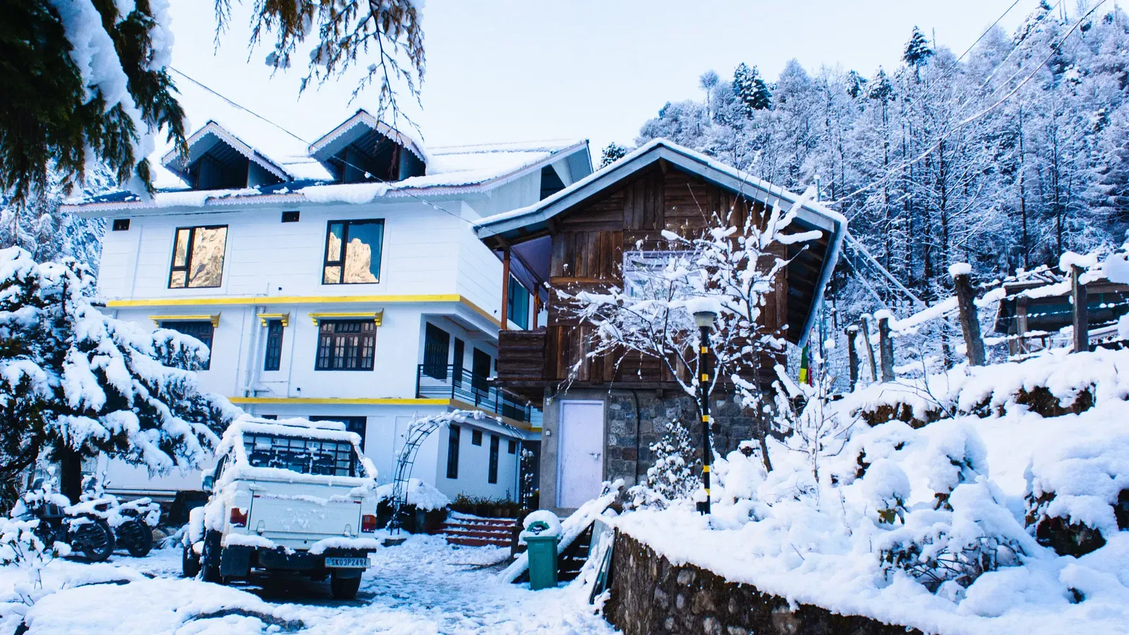  Snow-covered exterior of Avianna Mystique Valley, Lachung with chalet-style buildings and pine forest backdrop.