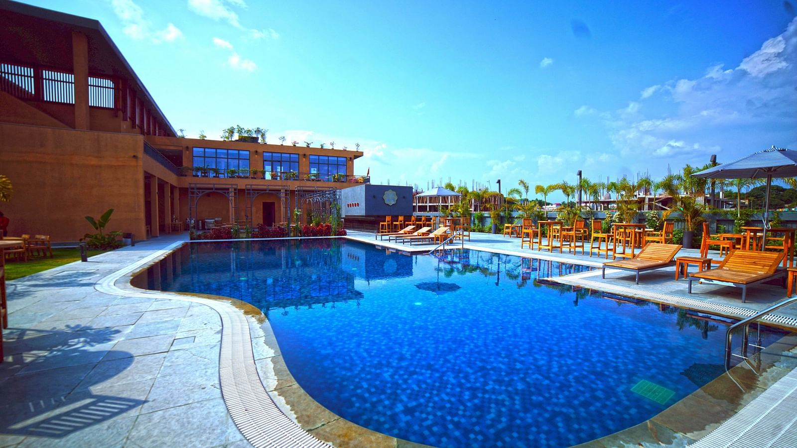 Outdoor swimming pool at Singalila Club with lounging chairs placed around the periphery