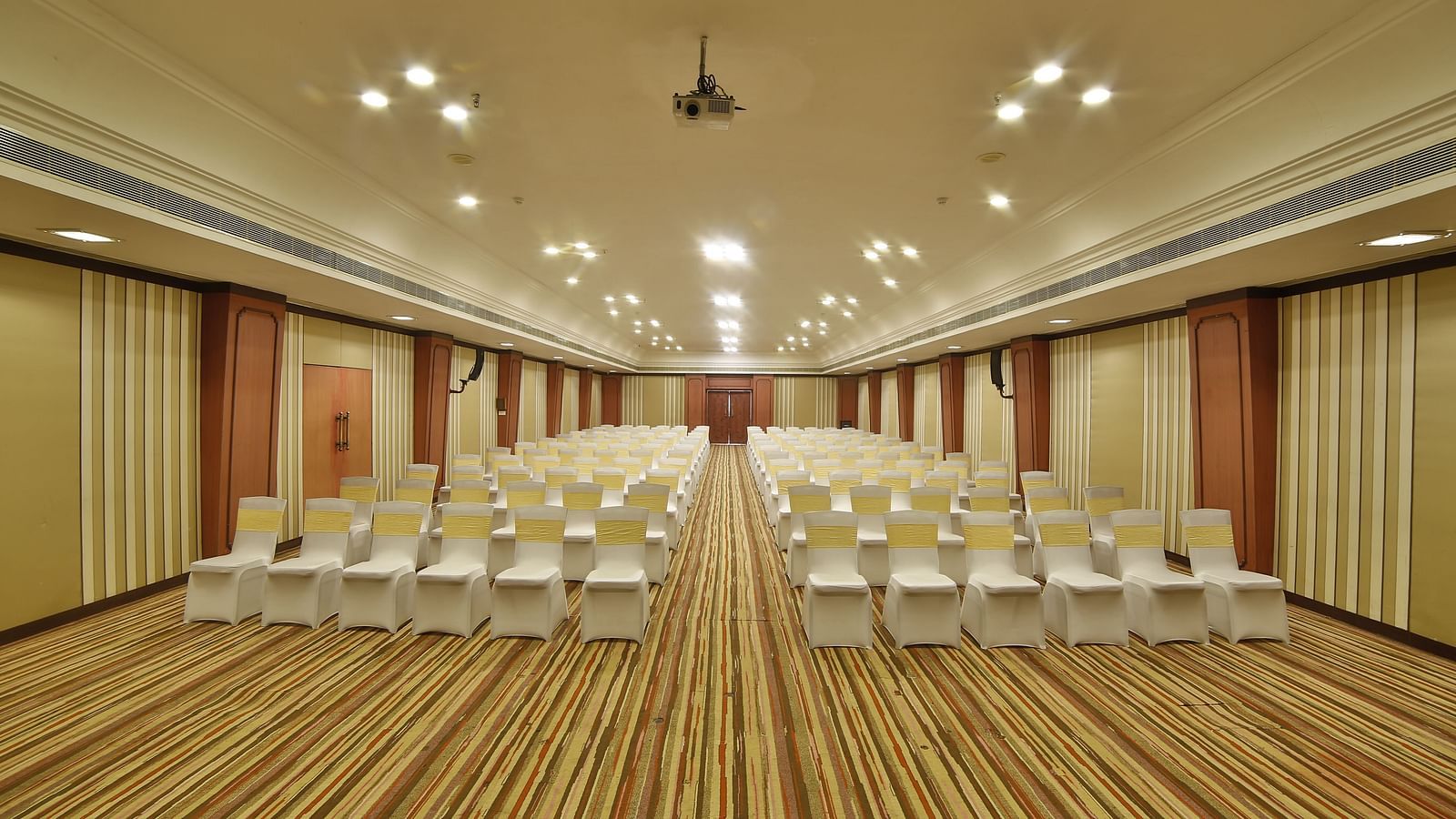  Seating arrangement in Terrace Hall A grand hotel suite with an opulent red and white decor, large bed, and seating area, reflecting a traditional style at Sitara Luxury Hotel in Hyderabad near Ramoji Film City.