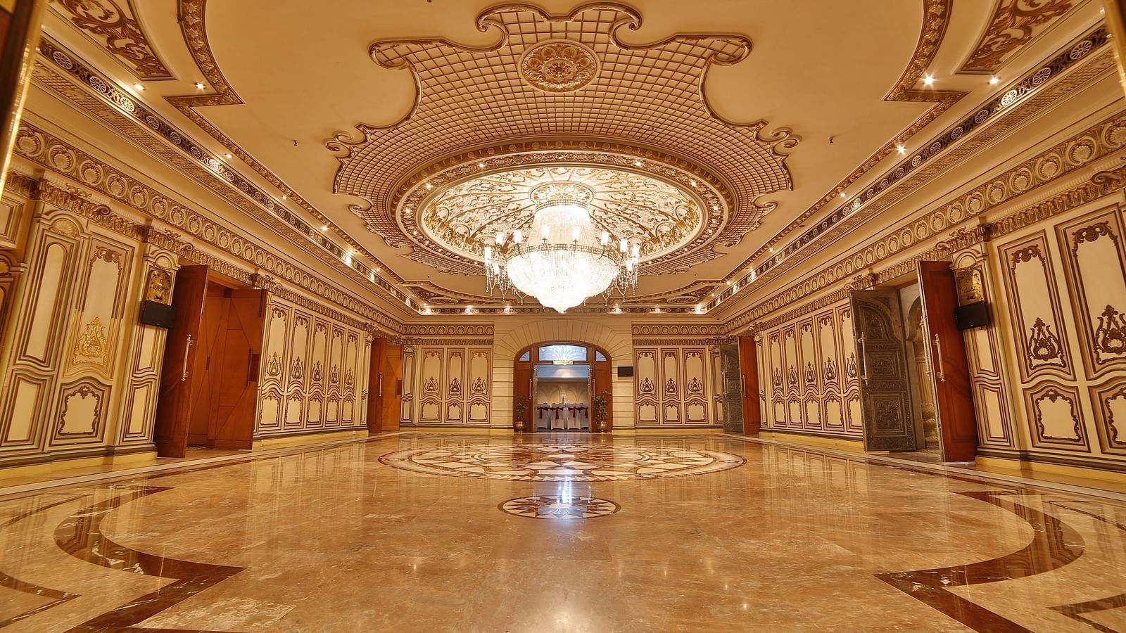 Interiors of Rang Mahal hall A grand hotel suite with an opulent red and white decor, large bed, and seating area, reflecting a traditional style at Sitara Luxury Hotel in Hyderabad near Ramoji Film City.