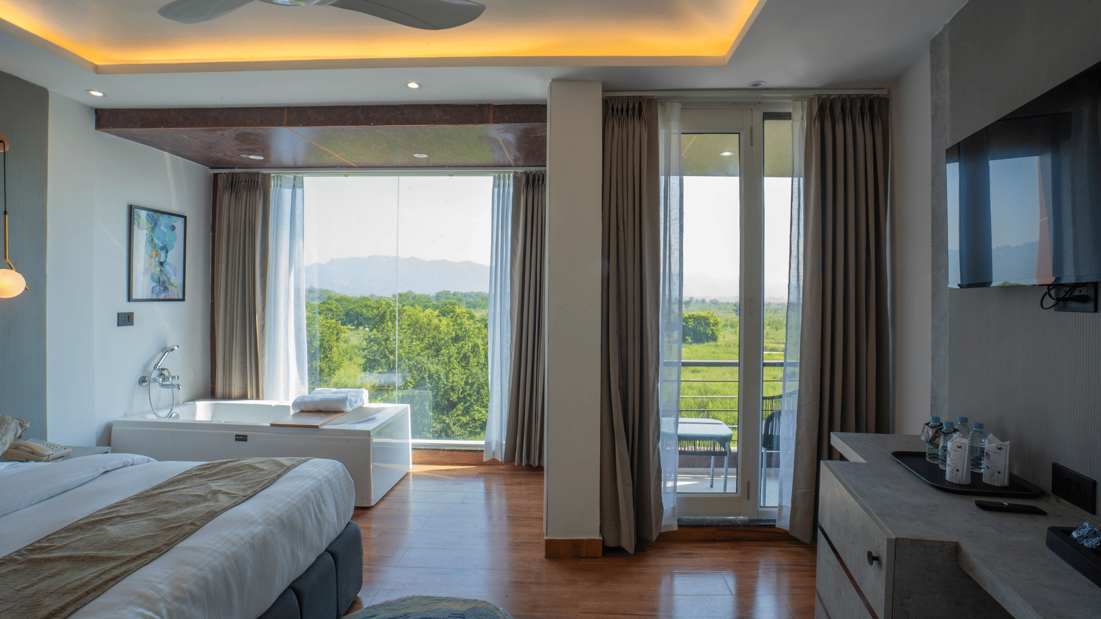 A guest room at Sukoon by the Ganges featuring a large bed, a bathtub by the window, and a door leading to a balcony.