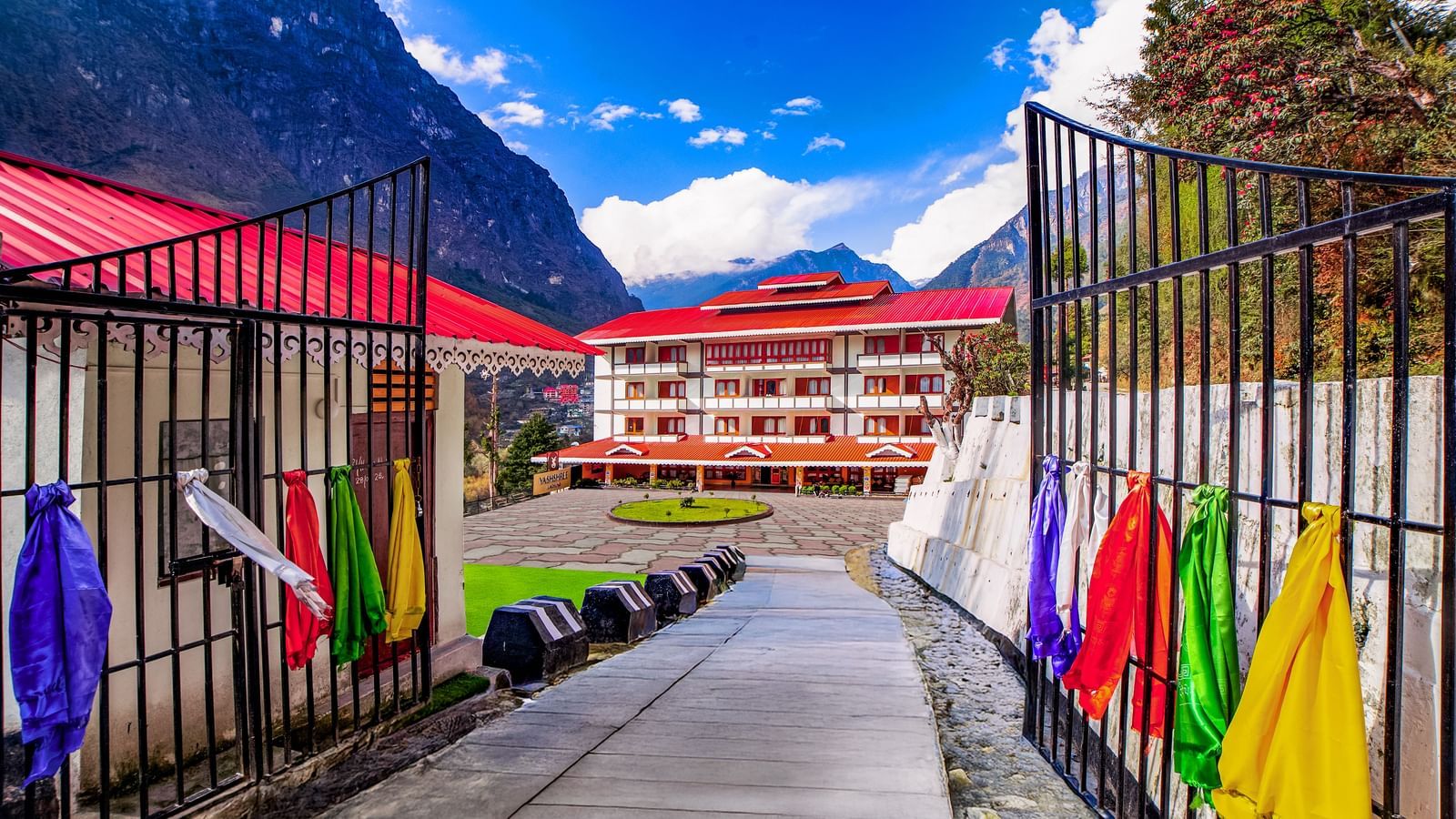 Exterior view of Yashshree Lachung hotel, set against mountain backdrops with colourful railings leading to the welcoming property entrance.
