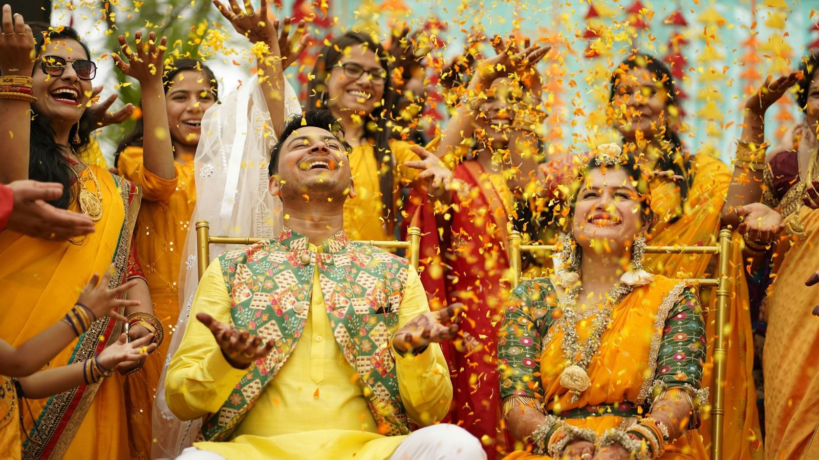Joyful moment of a Hindu wedding ceremony with the couple seated before the sacred fire surrounded by colourful floral decorations and family.