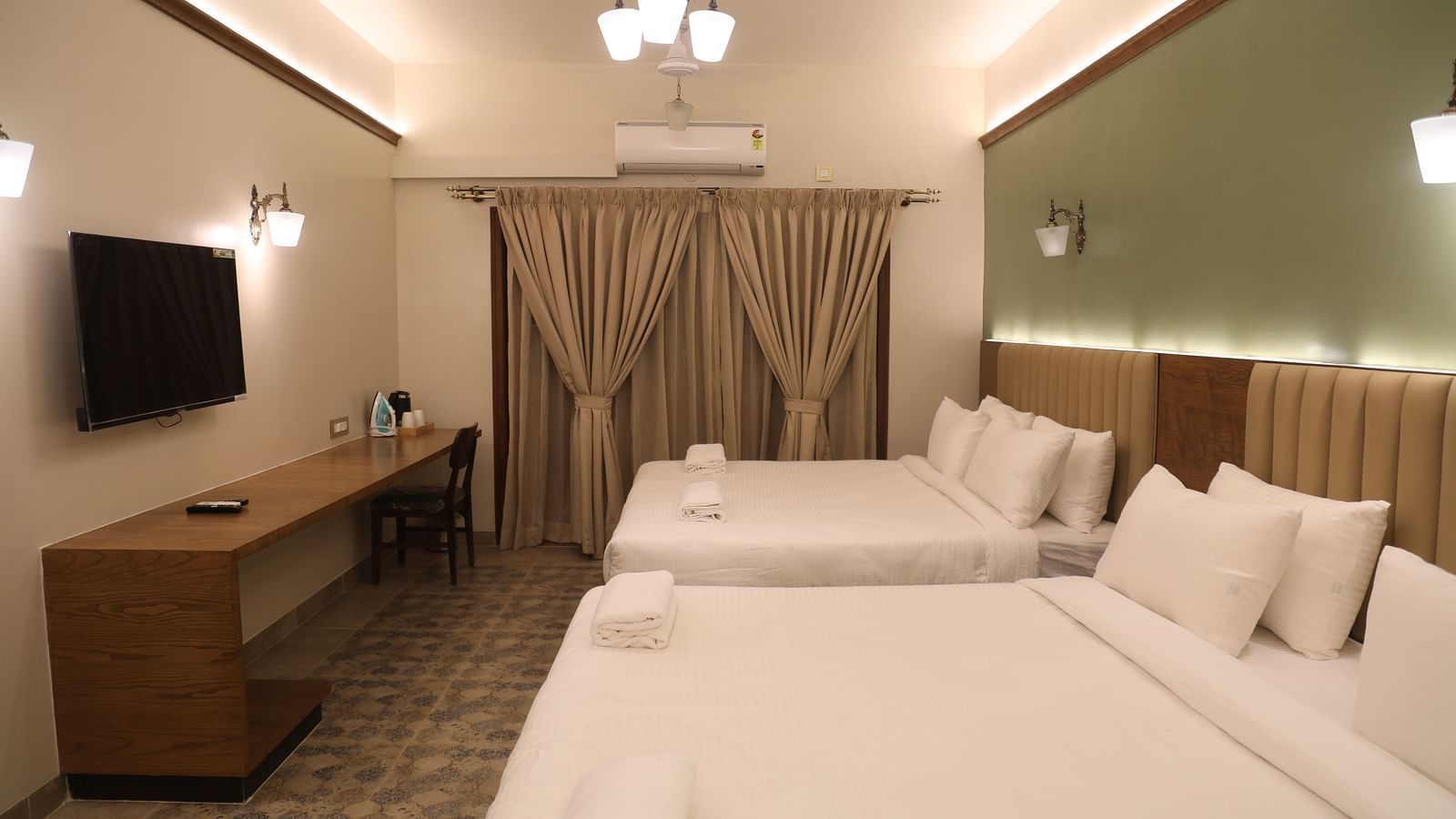 two double beds and a television inside on of the Heritage Suites at Summer House, Nandi Hills