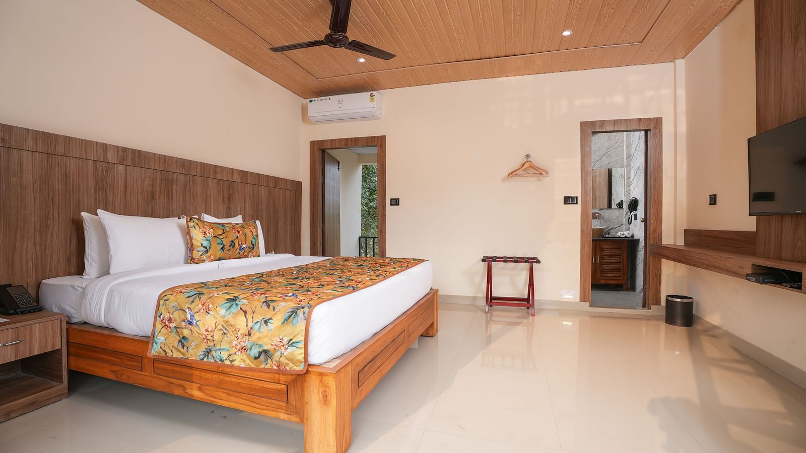 Bungalow featuring a spacious bed with a wall-mounted television and a large balcony at Summit Green Lake Tea Resort & Spa, Kaziranga2.