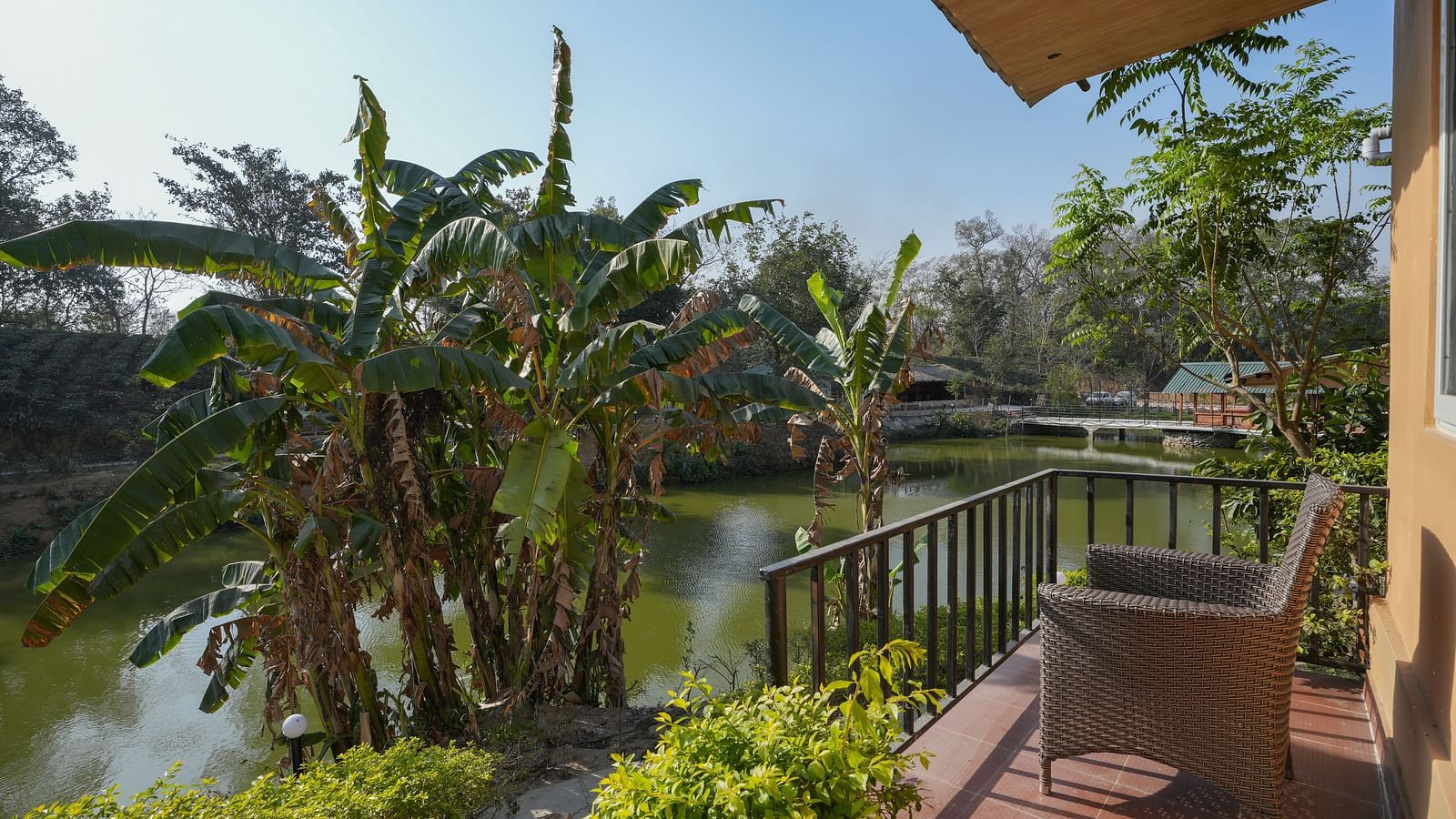 Deluxe Cottage featuring a lake view with cushioned seating at Summit Green Lake Tea Resort & Spa, Kaziranga