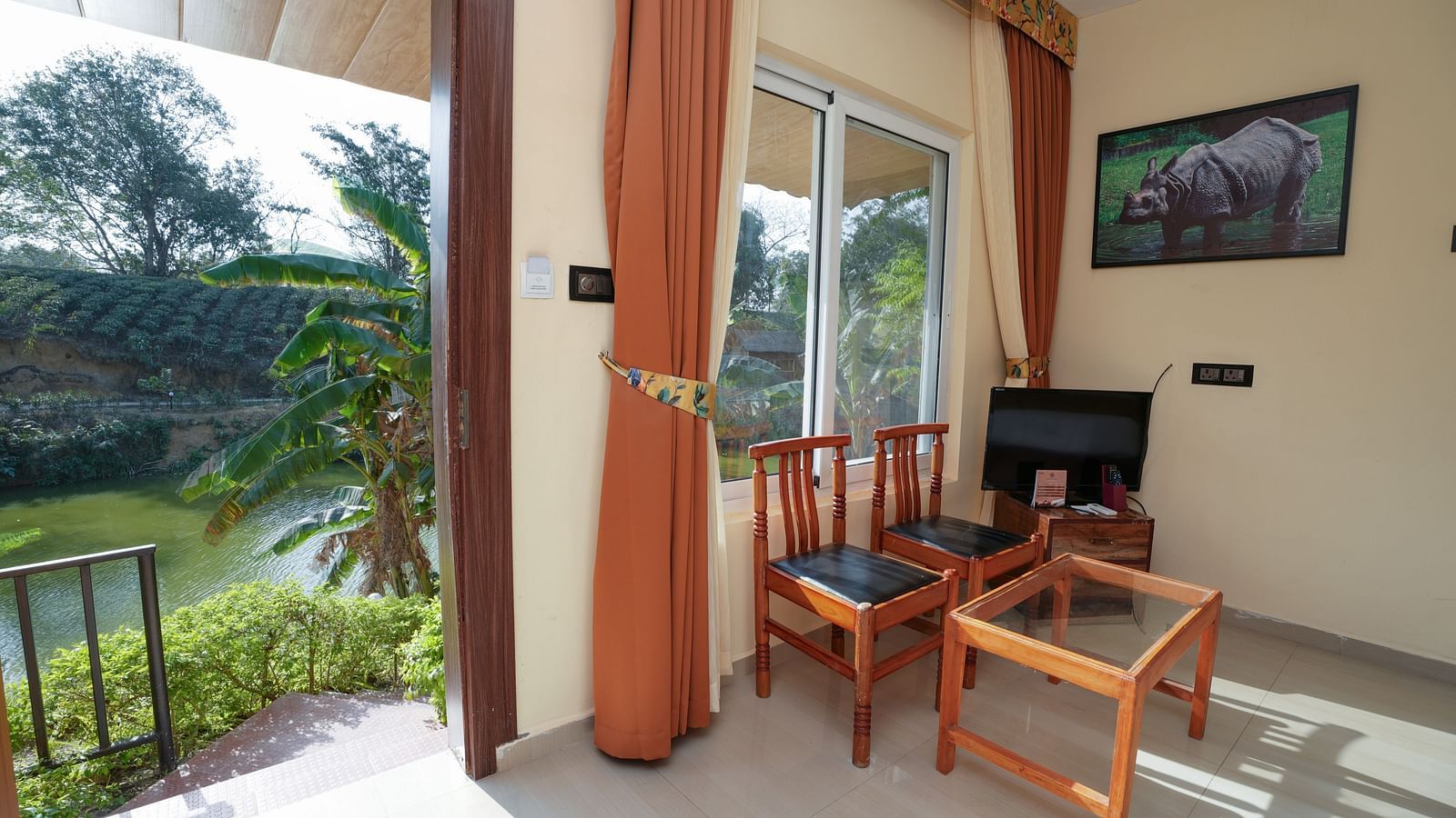 Deluxe Cottage featuring lake view, television, air conditioner, glass table, and chairs at Summit Green Lake Tea Resort & Spa, Kaziranga