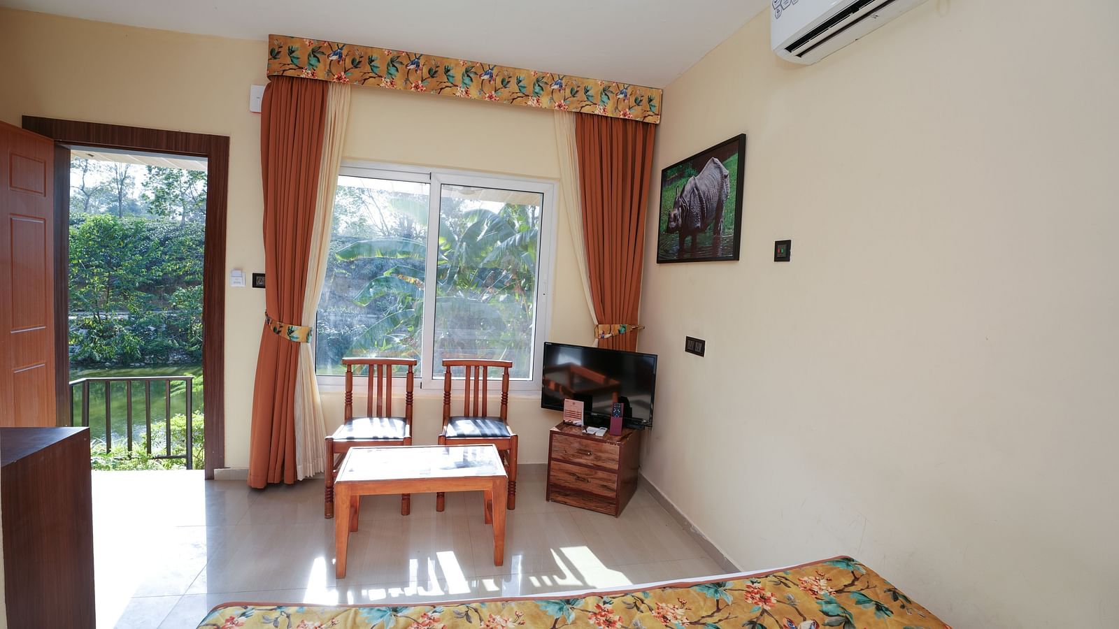 Deluxe Cottage featuring lake view, television, air conditioner, glass table, and chairs, large windows at Summit Green Lake Tea Resort & Spa, Kaziranga.