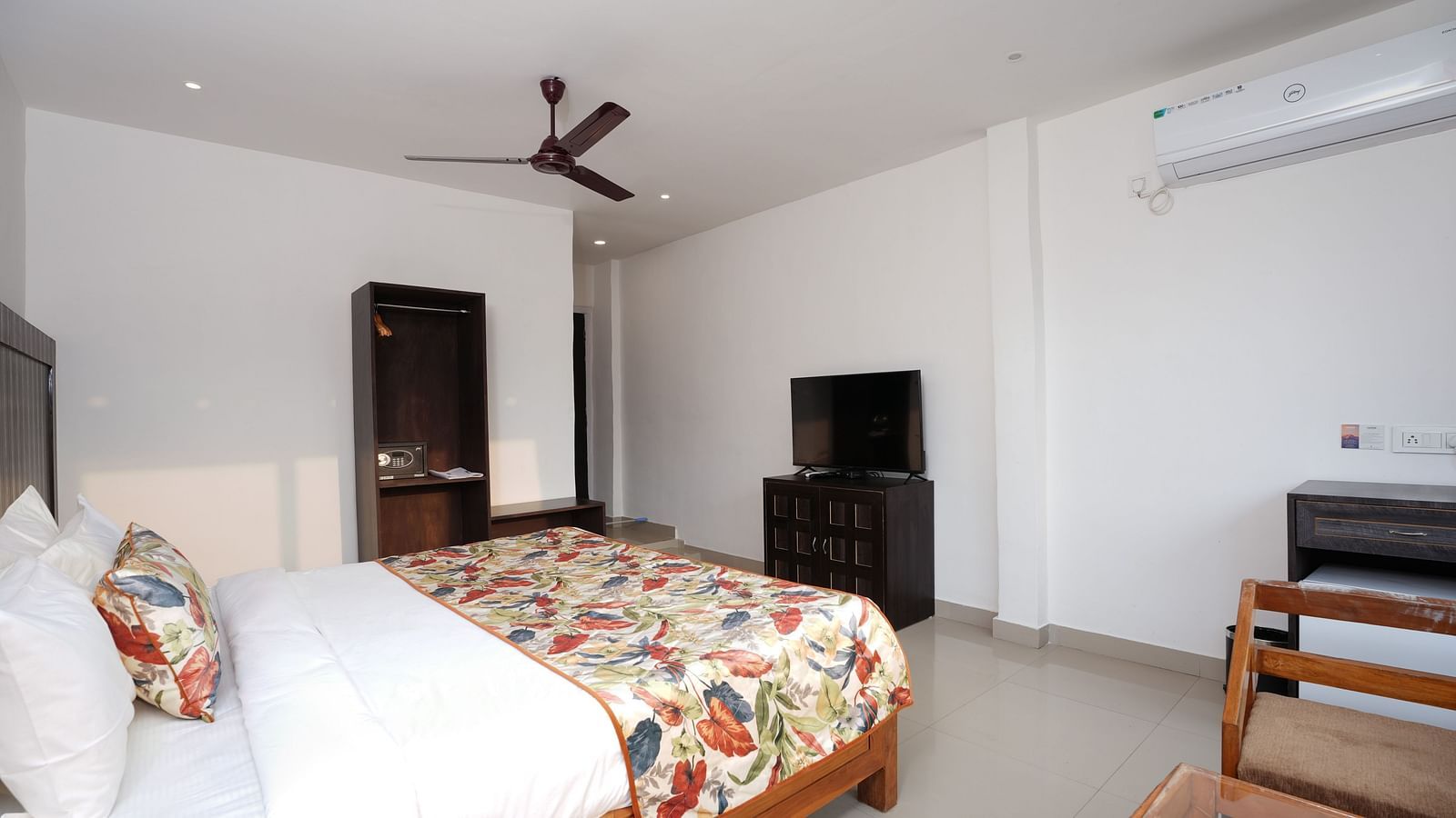 Deluxe room featuring large windows with a nature view, a spacious bed, air conditioning, wooden storage units, and a television at Summit Green Lake Tea Resort & Spa, Kaziranga8