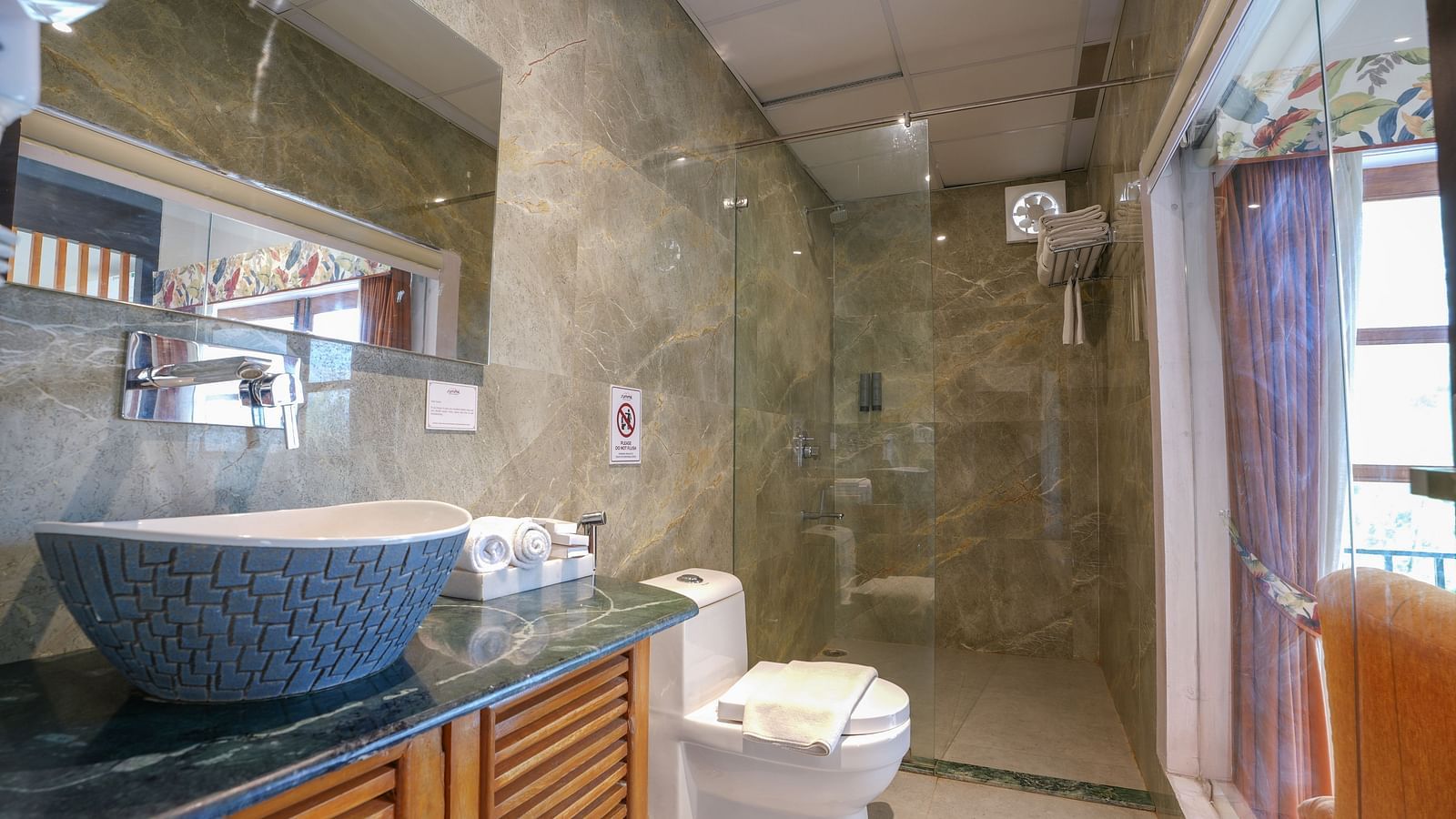 In the Suite with Balcony, the spacious bathroom features a large washbasin with a mirror and a glass partition dividing the shower area at Summit Green Lake Tea Resort & Spa, Kaziranga