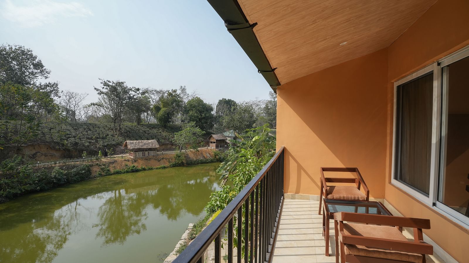 Premium room with balcony featuring a lake view and wooden furniture & glass table for enjoying the scenery at Summit Green Lake Tea Resort & Spa, Kaziranga
