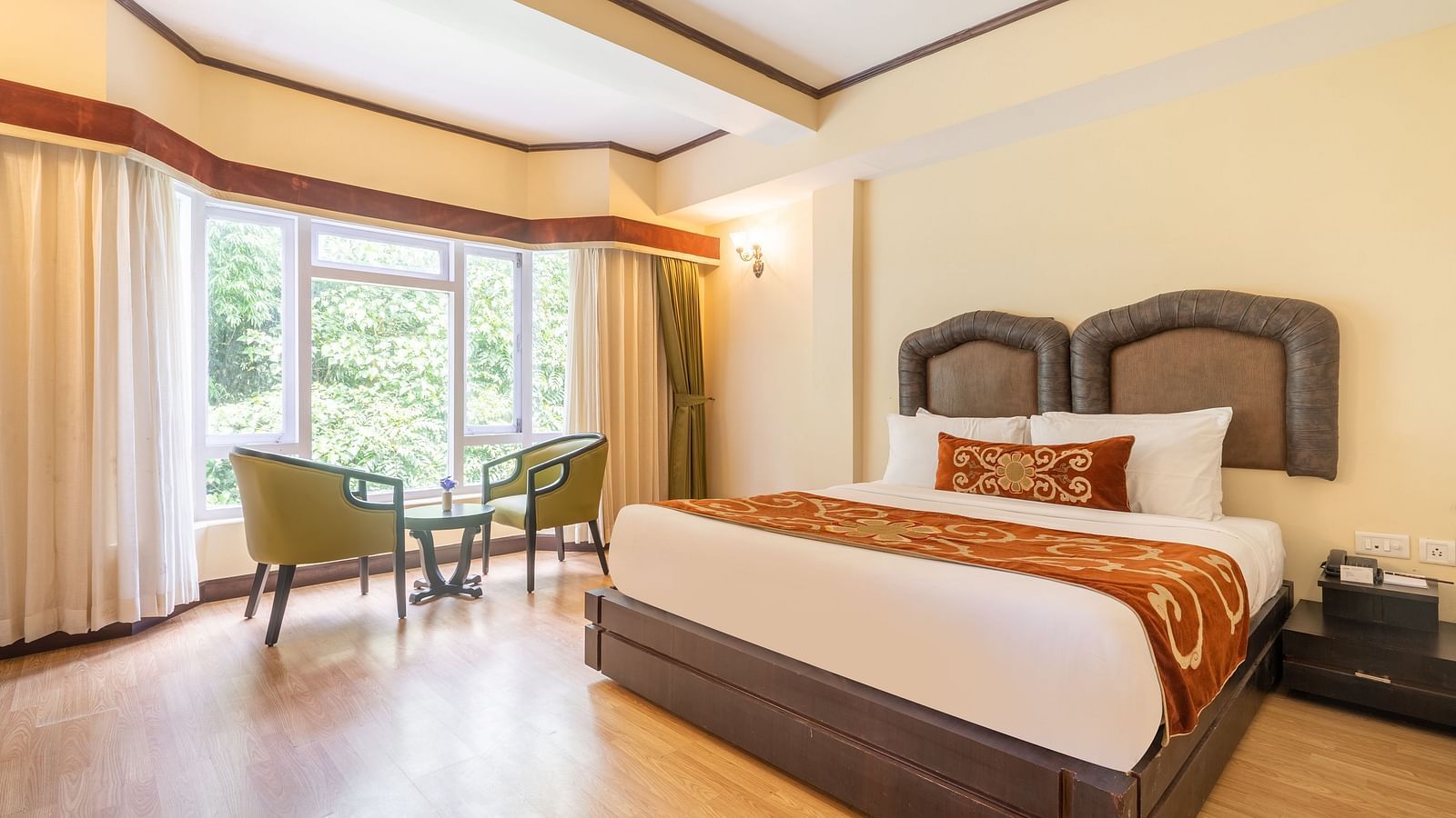 king size bed  with chairs near balcony of deluxe bed at Summit Lillium Hotel & Spa, Kalimpong