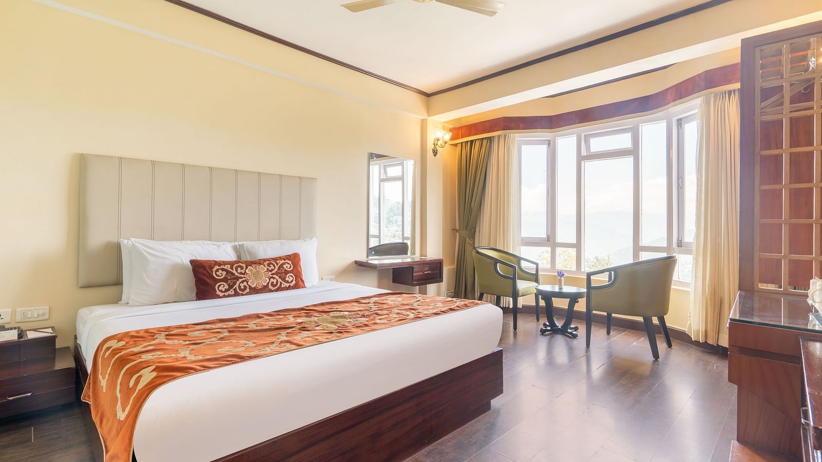 king size bed and chairs in the background near balcony of premium room at Summit Lillium Hotel & Spa, Kalimpong