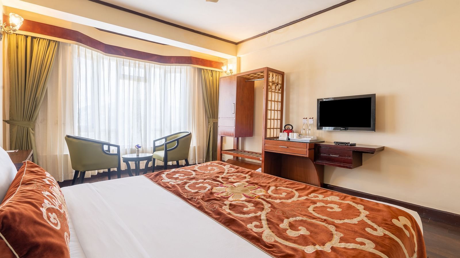 king size bed and chairs in the background near balcony of premium room at Summit Lillium Hotel & Spa, Kalimpong