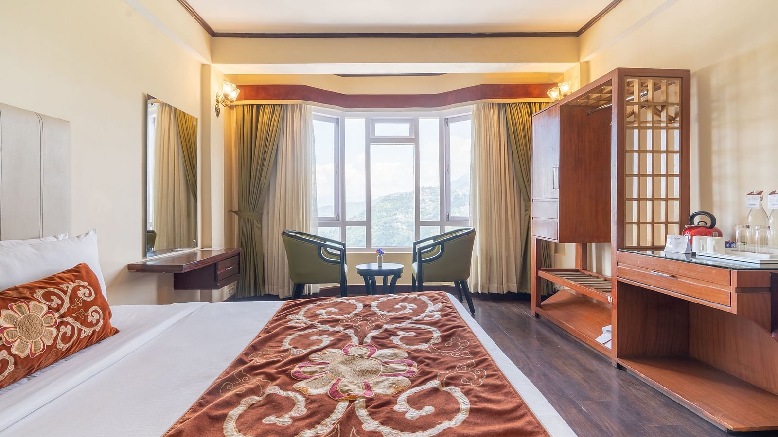 king size bed and chairs in the background near balcony of premium room at Summit Lillium Hotel & Spa, Kalimpong