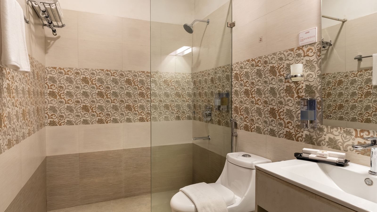 Bathroom at Summit North Star, Gangtok featuring a commode, shower area with shower screen and shower head, a wash basin and a faucet, and other toiletries like towels, handwash, etc.