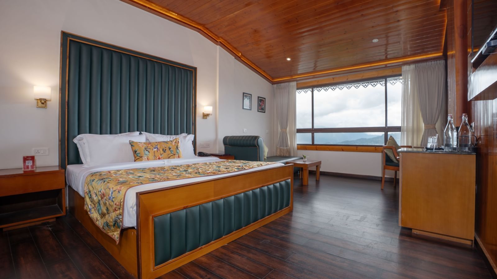 Premium Valley View Room at Summit North Star, Gangtok featuring a bed, a cabinet table, a seating area, and a large window with valley view.