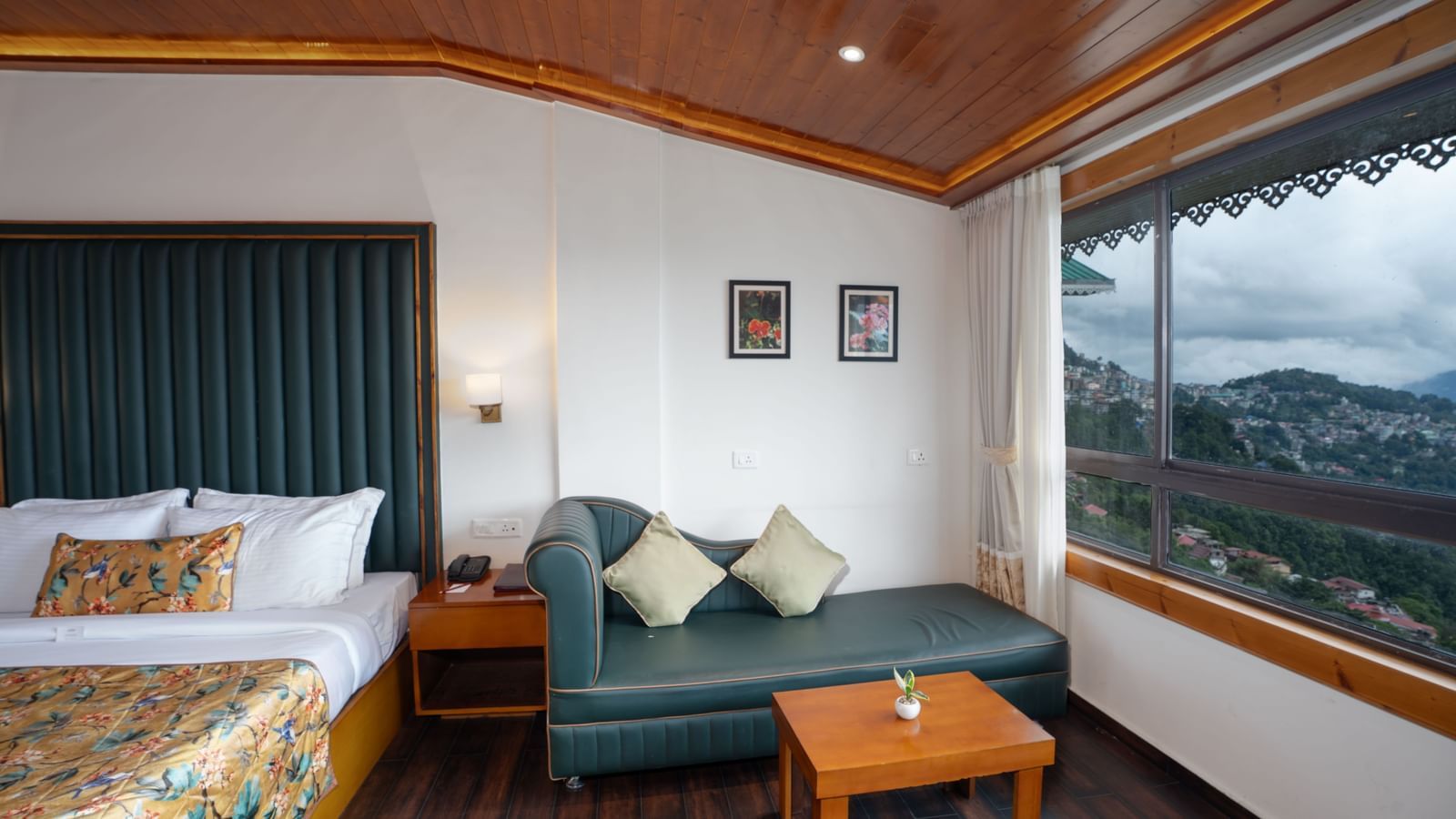 Premium Valley View Room at Summit North Star, Gangtok featuring a bed, a sofa chair, a centre table, and a large window.
