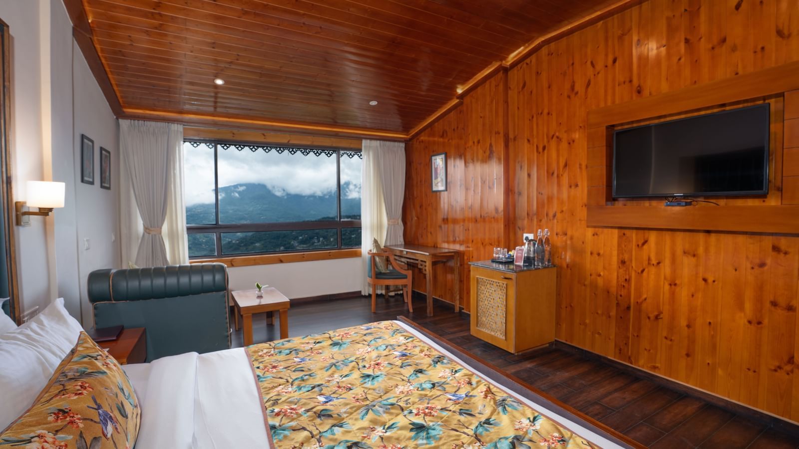 Premium Valley View Room featuring a bed, a flat TV screen, a cabinet table, a work desk and chair, a sofa, and a large window.