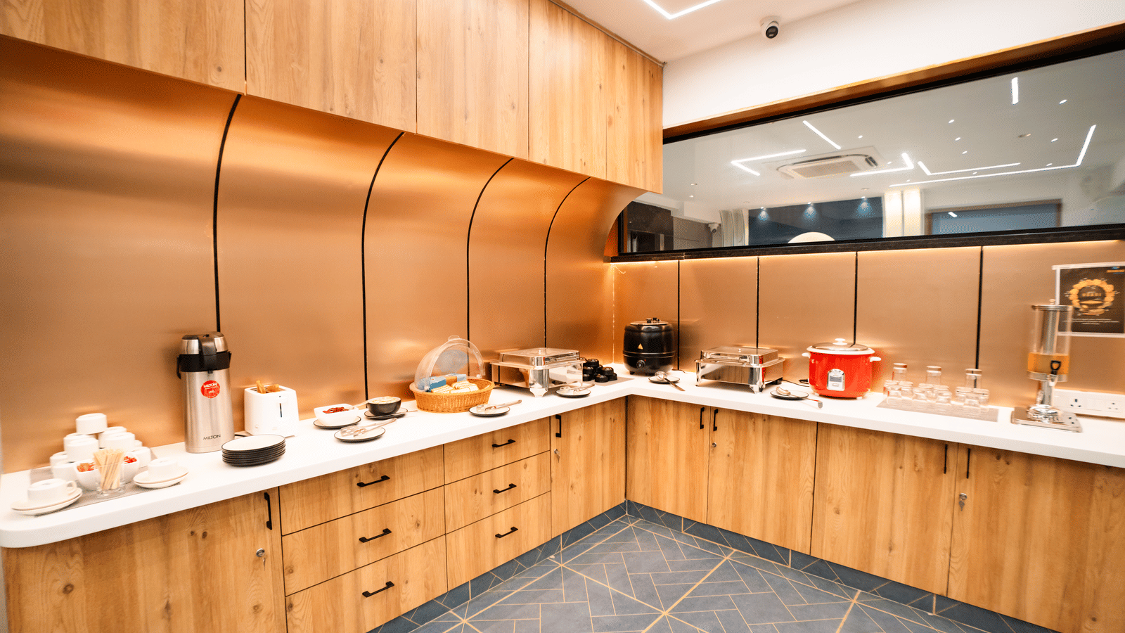 Dining area with buffet setup on an L-shaped counter featuring various dishes and cutlery at Sunrise Business Hotel, Hyderabad.