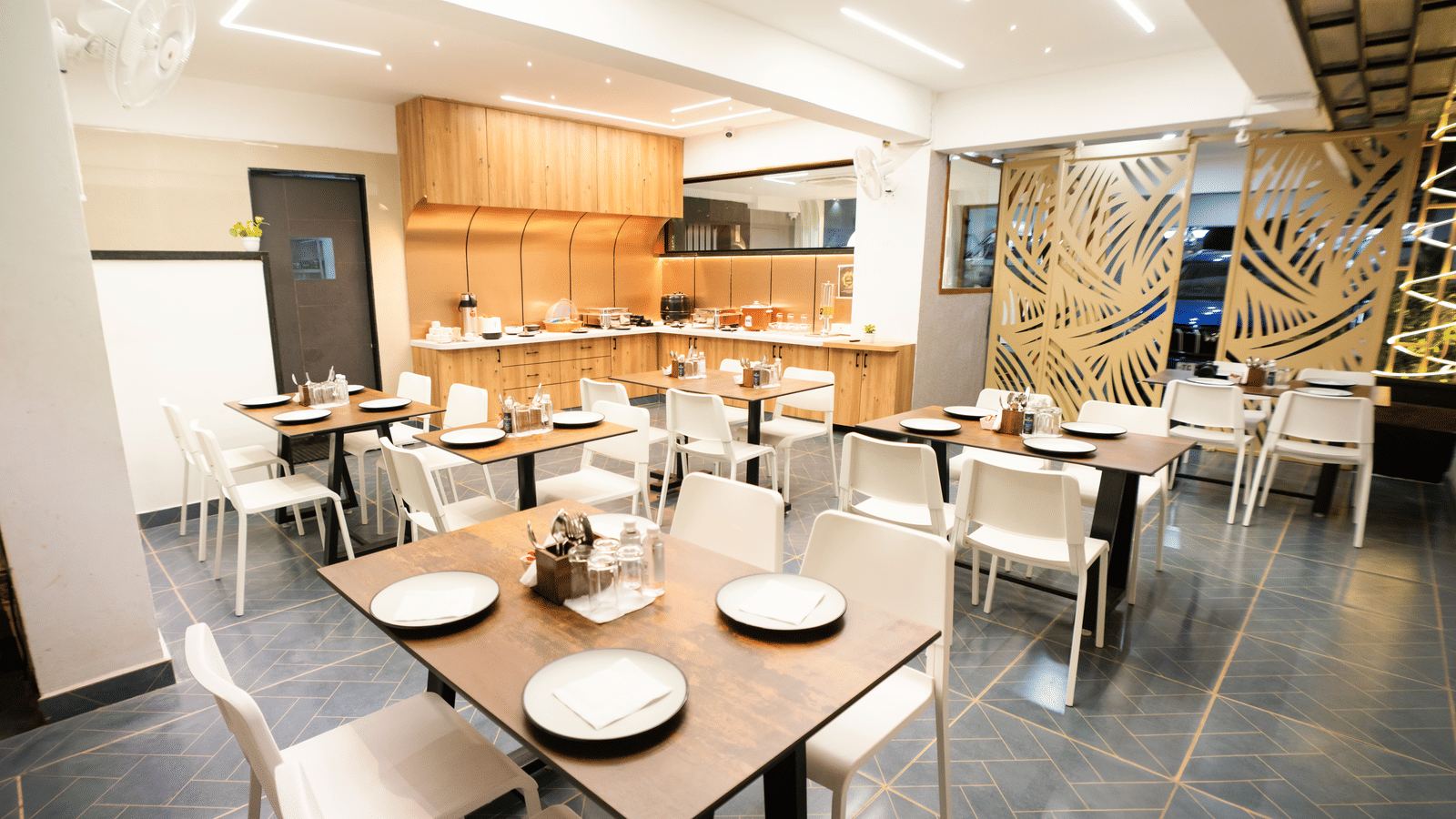 Restaurant seating area with tables and chairs set for dining at Sunrise Business Hotel, Hyderabad.