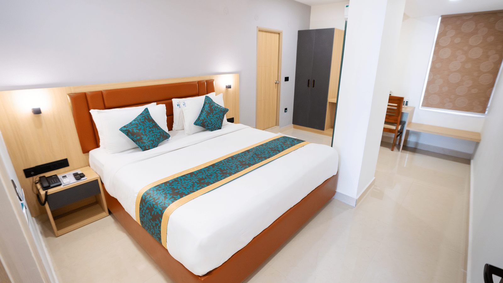 A spacious room with a large bed, a bedside table, and a doorway to the side at Sunrise Business Hotel, Hyderabad.