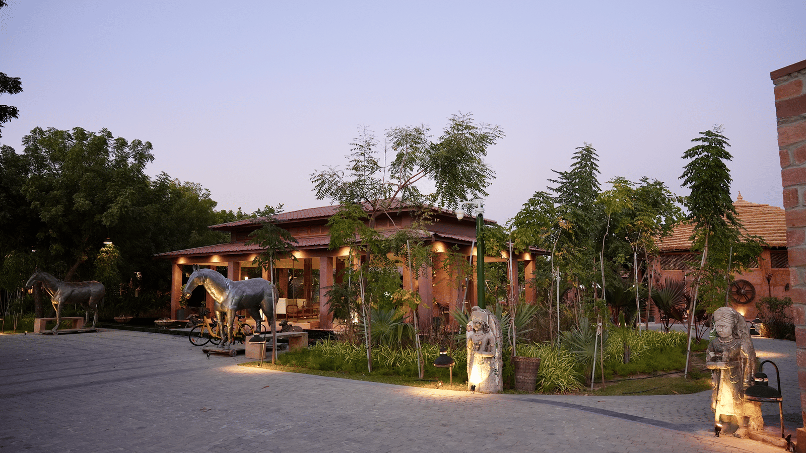 Facade of Surpura Bagh with trees surrounding it and a pathway leading to the reception under evening sky