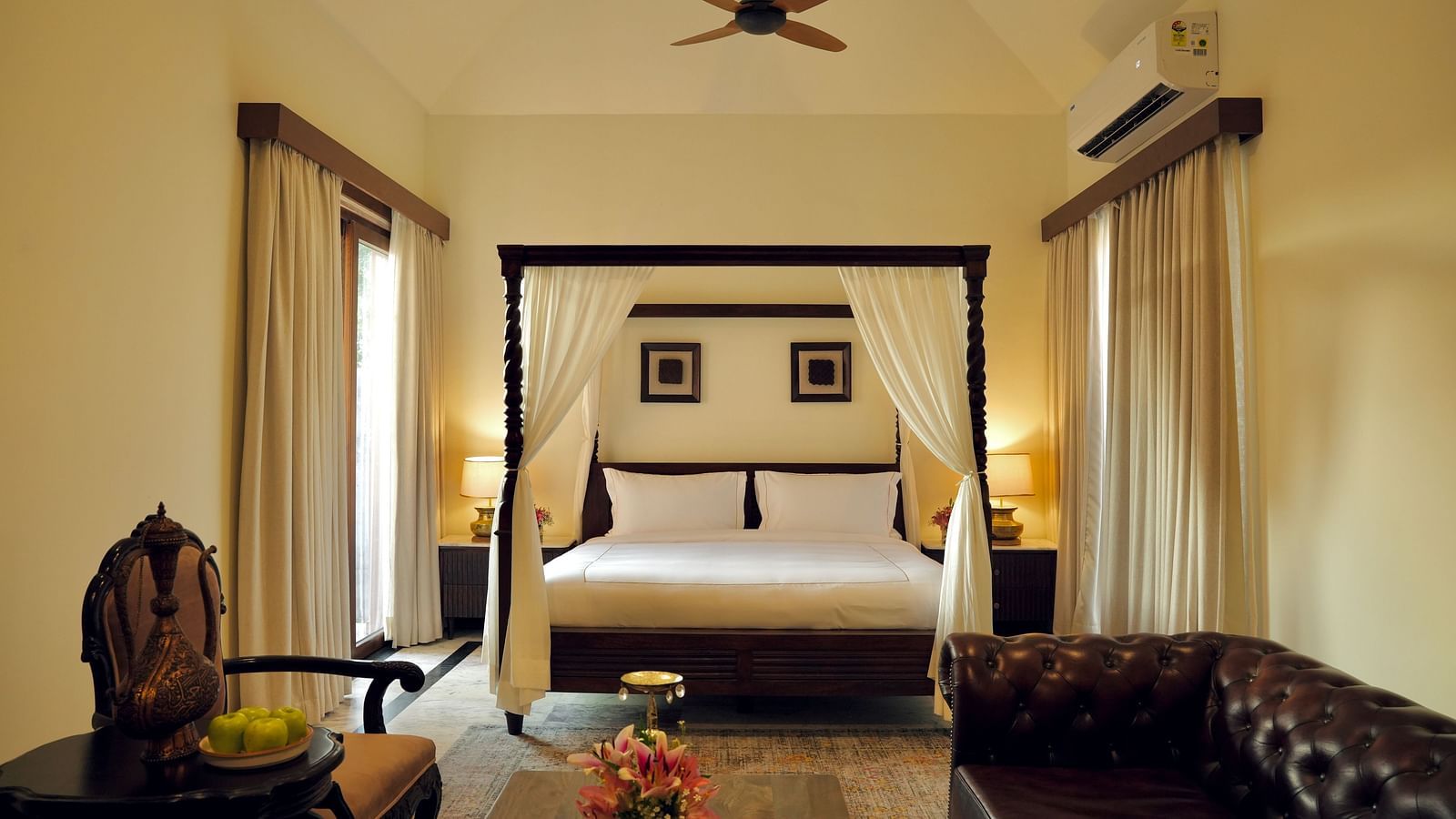 A room with a bed and a seating area in front of it at Surpura Bagh.
