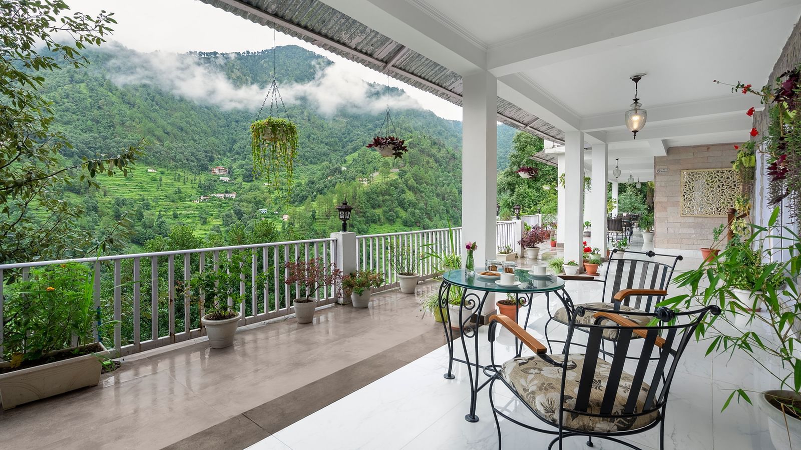 An image of a courtyard filled with flower pots and at the centre there is are three chairs and a table - Suvaasa, Ramgarh 
