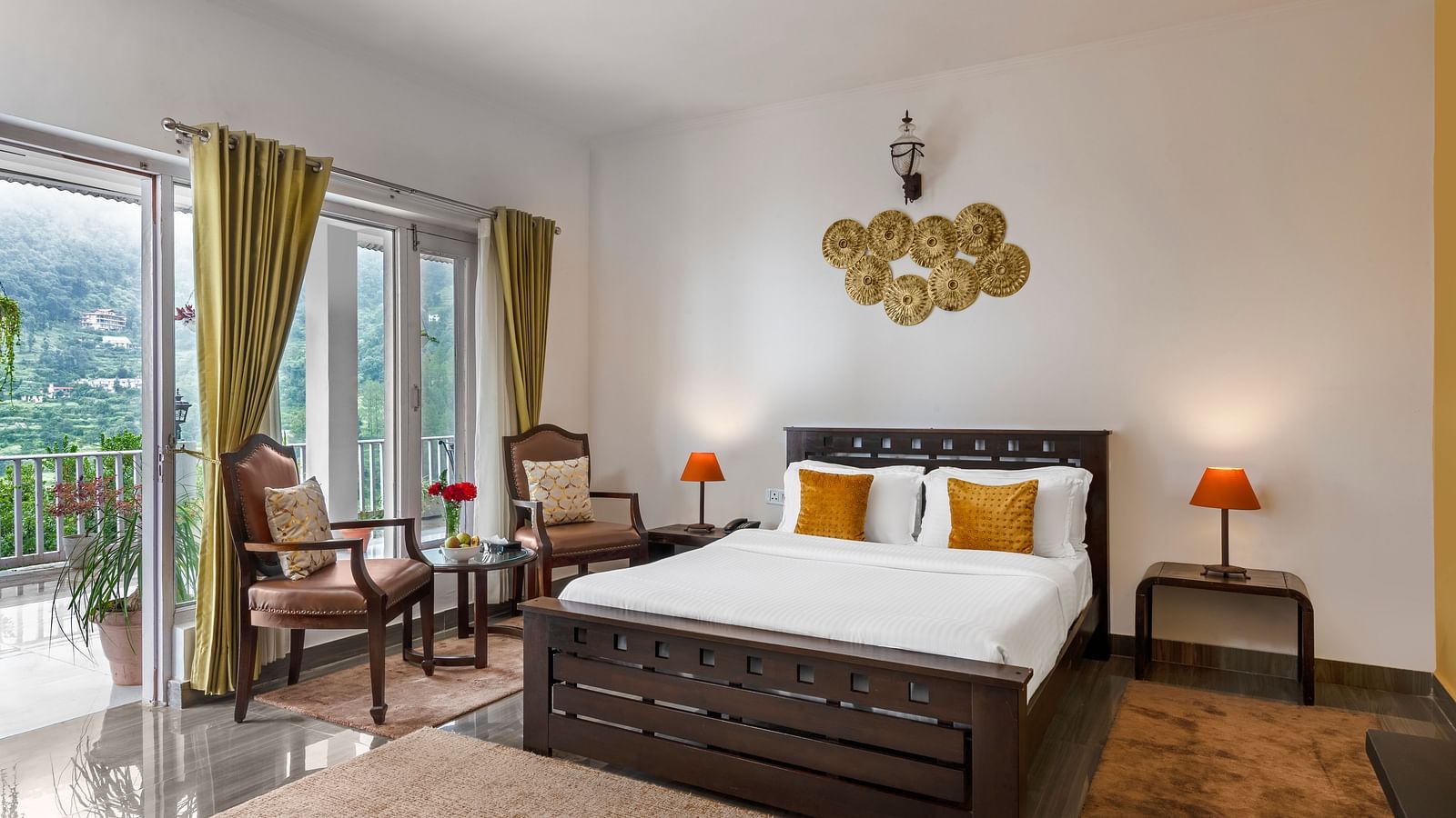 An image of a bedroom with a king size bed, bedside table with lamps, and two chairs with a centre tabl  - Suvaasa, Ramgarh