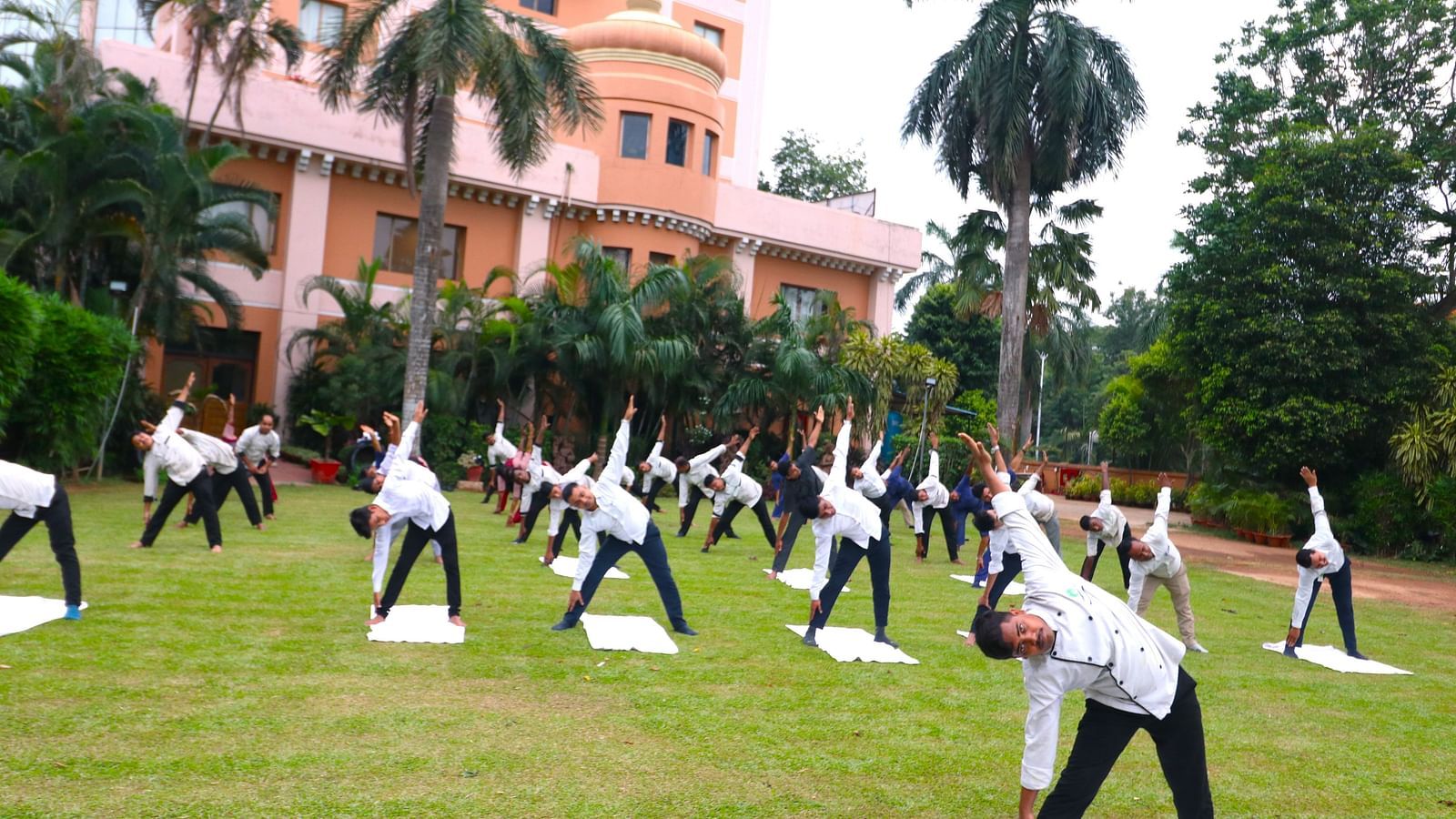 People practising yoga in the garden area at Swosti Resorts on a sunny day