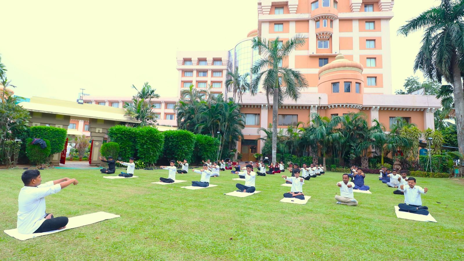 People practising yoga in the garden area at Swosti Resorts on a sunny day