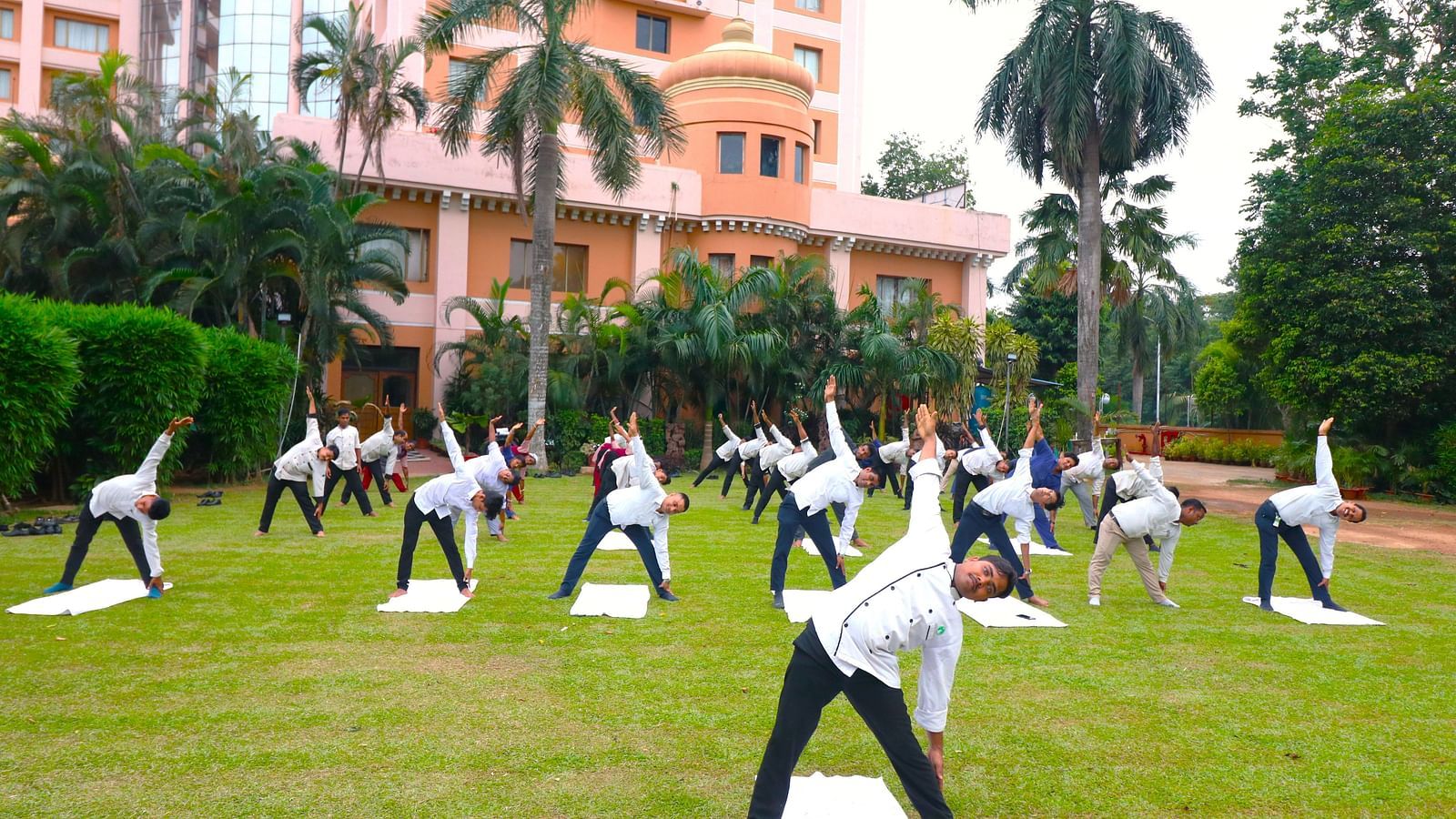 People practising yoga in the garden area at Swosti Resorts on a sunny day